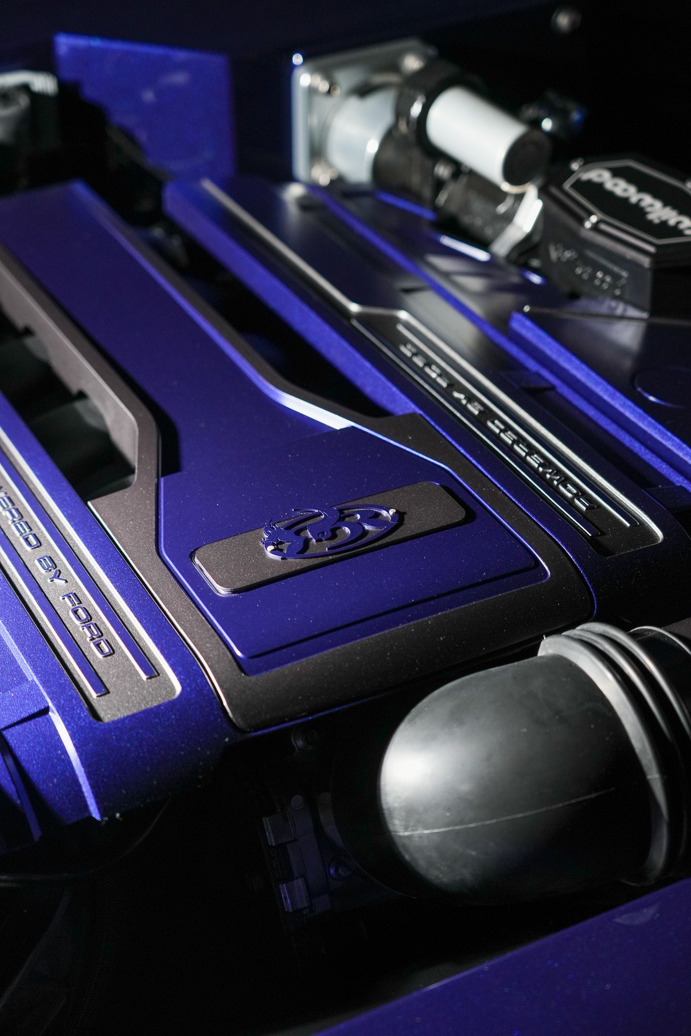 Close-up of blue metallic car engine cover with black accents.