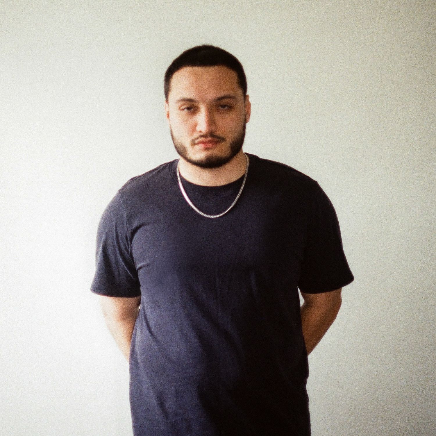 Person in black t-shirt standing against white wall.