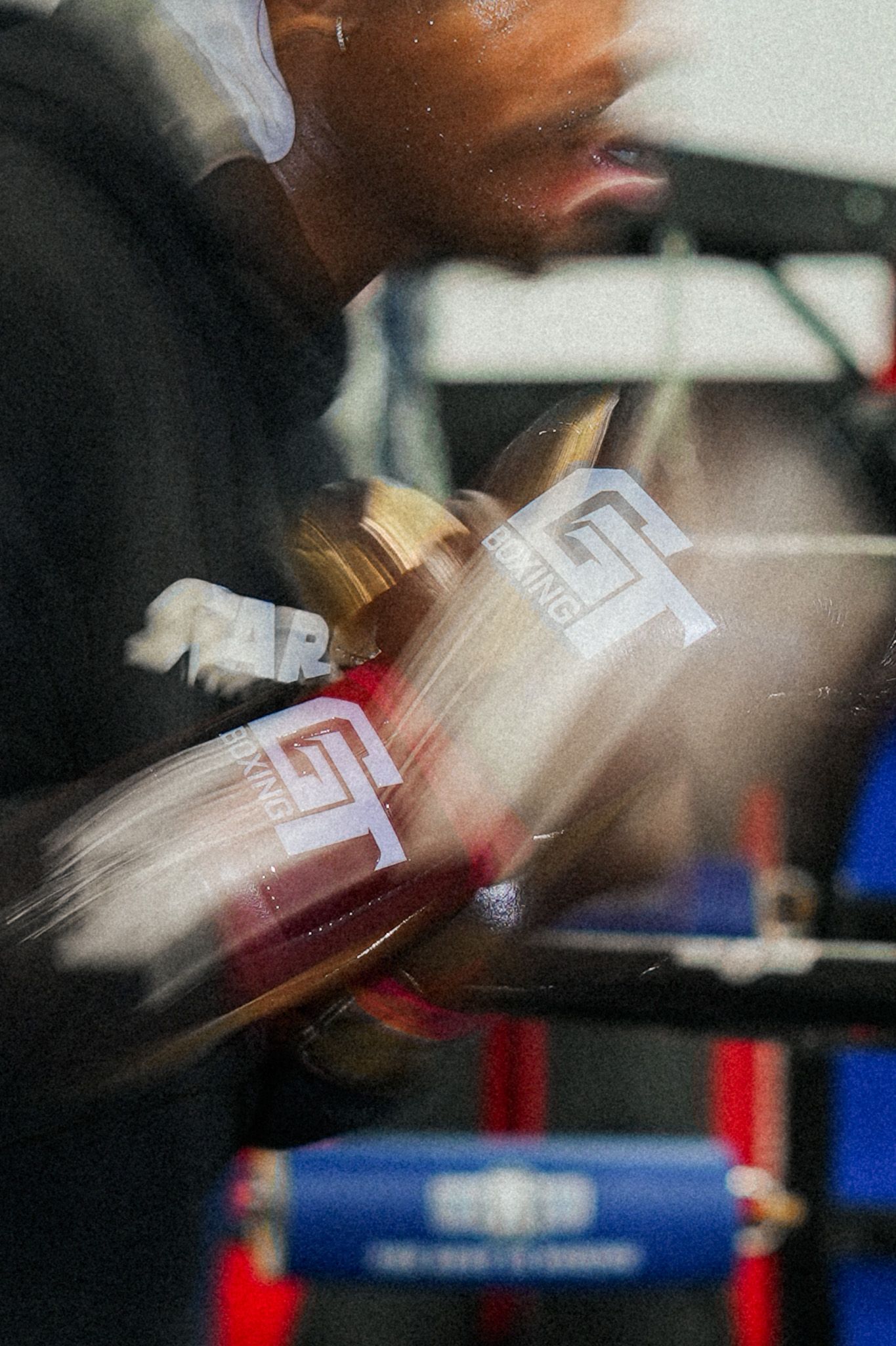 Blurred motion shot of boxing training with red and blue equipment in background.