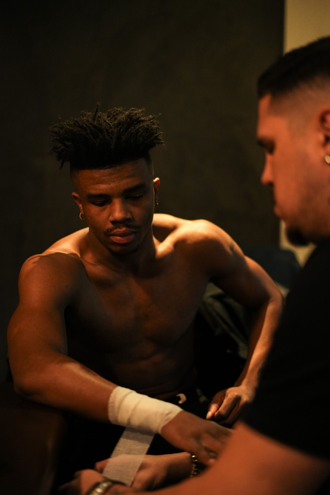 Dramatic low-light boxing training scene with athletes in dark atmospheric setting.