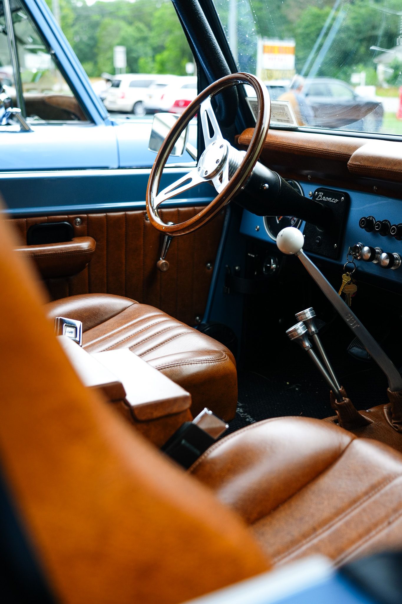 Brown leather vintage car interior with bench seat and steering wheel shown in warm lighting.
