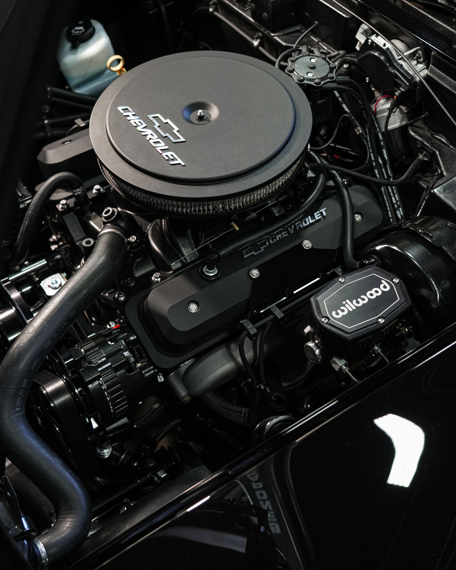 Black vintage car engine with chrome air cleaner and performance parts.