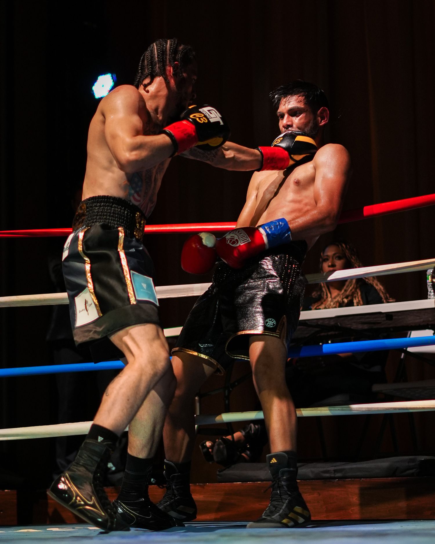 Two boxers sparring in a professional boxing ring during a match.