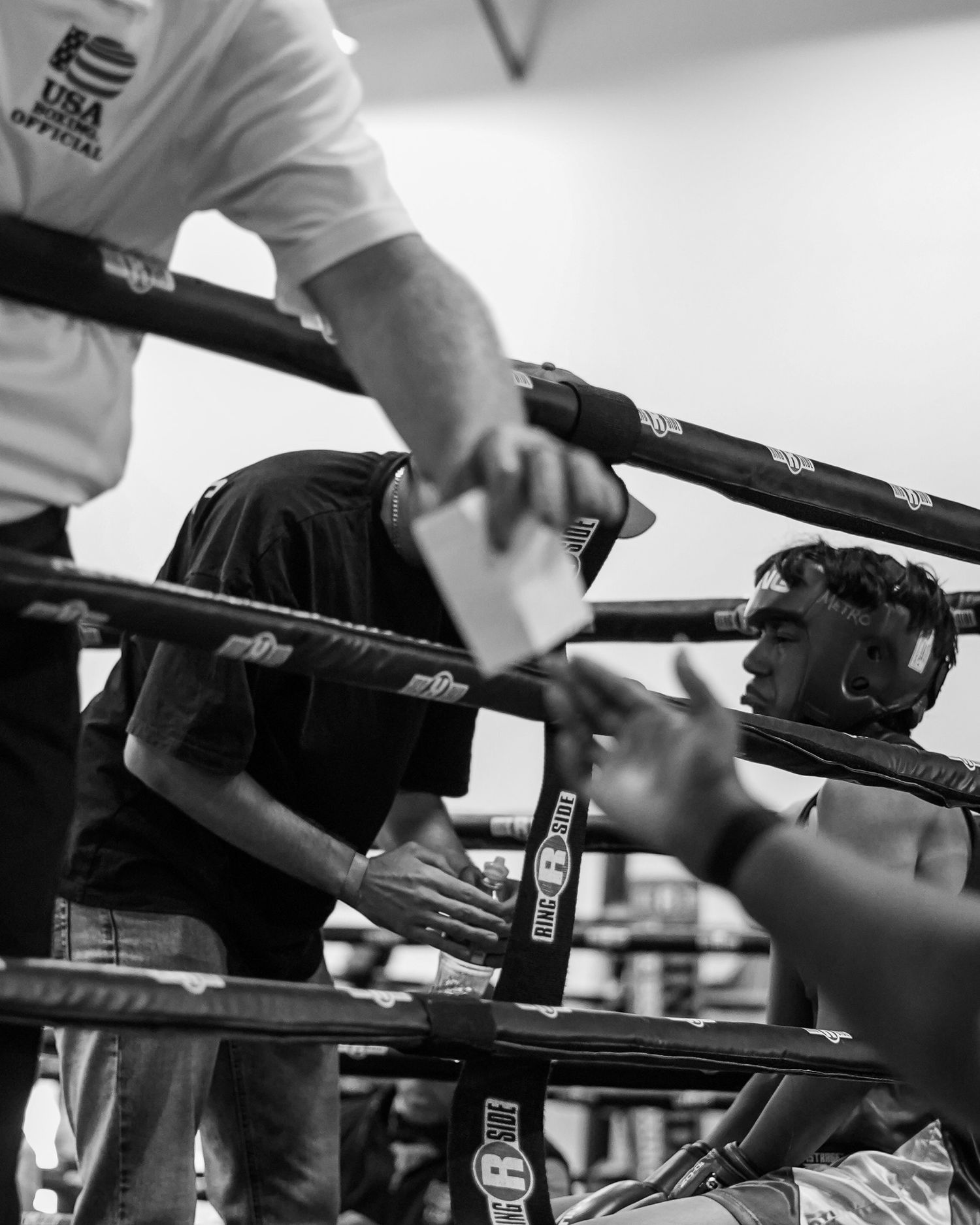 Boxer receives guidance through boxing ring ropes during intense match.