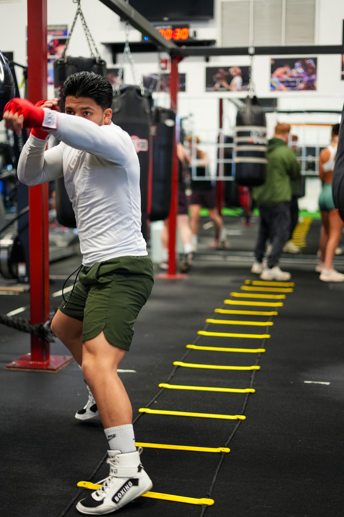 Person performing agility drills over yellow markers in fitness facility.