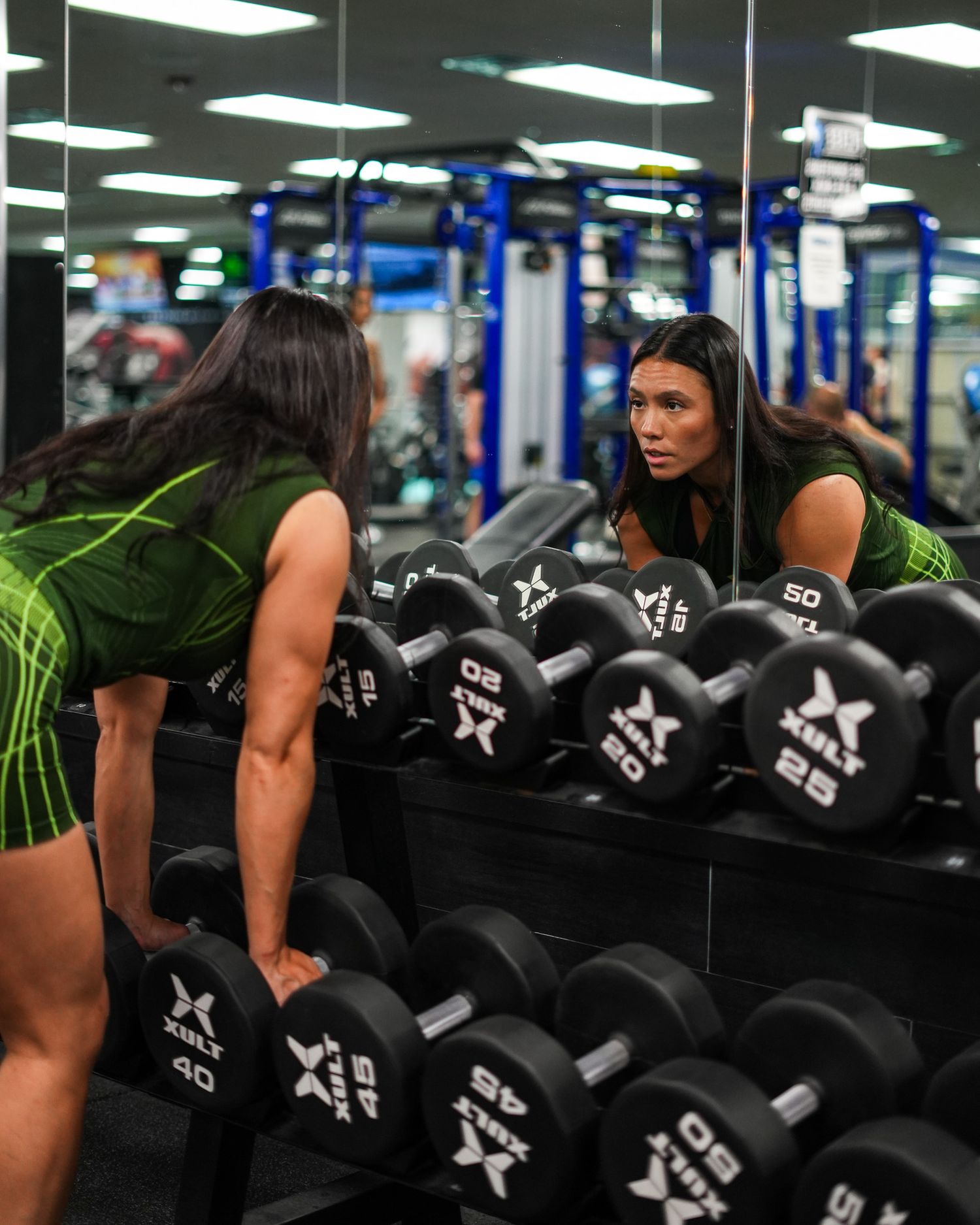 Row of black dumbbells lined up on rack in modern fitness facility.