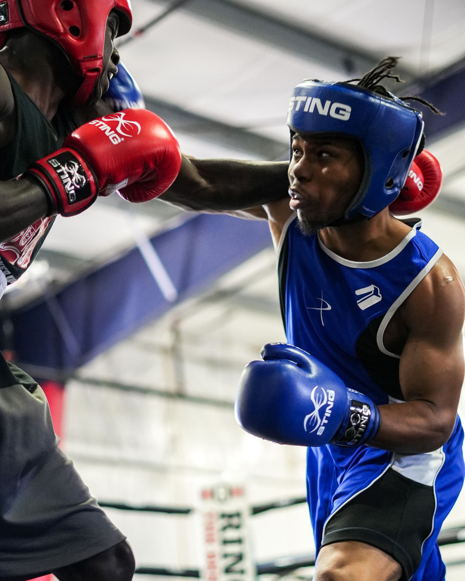 Boxers in protective headgear exchange punches during intense sparring match.
