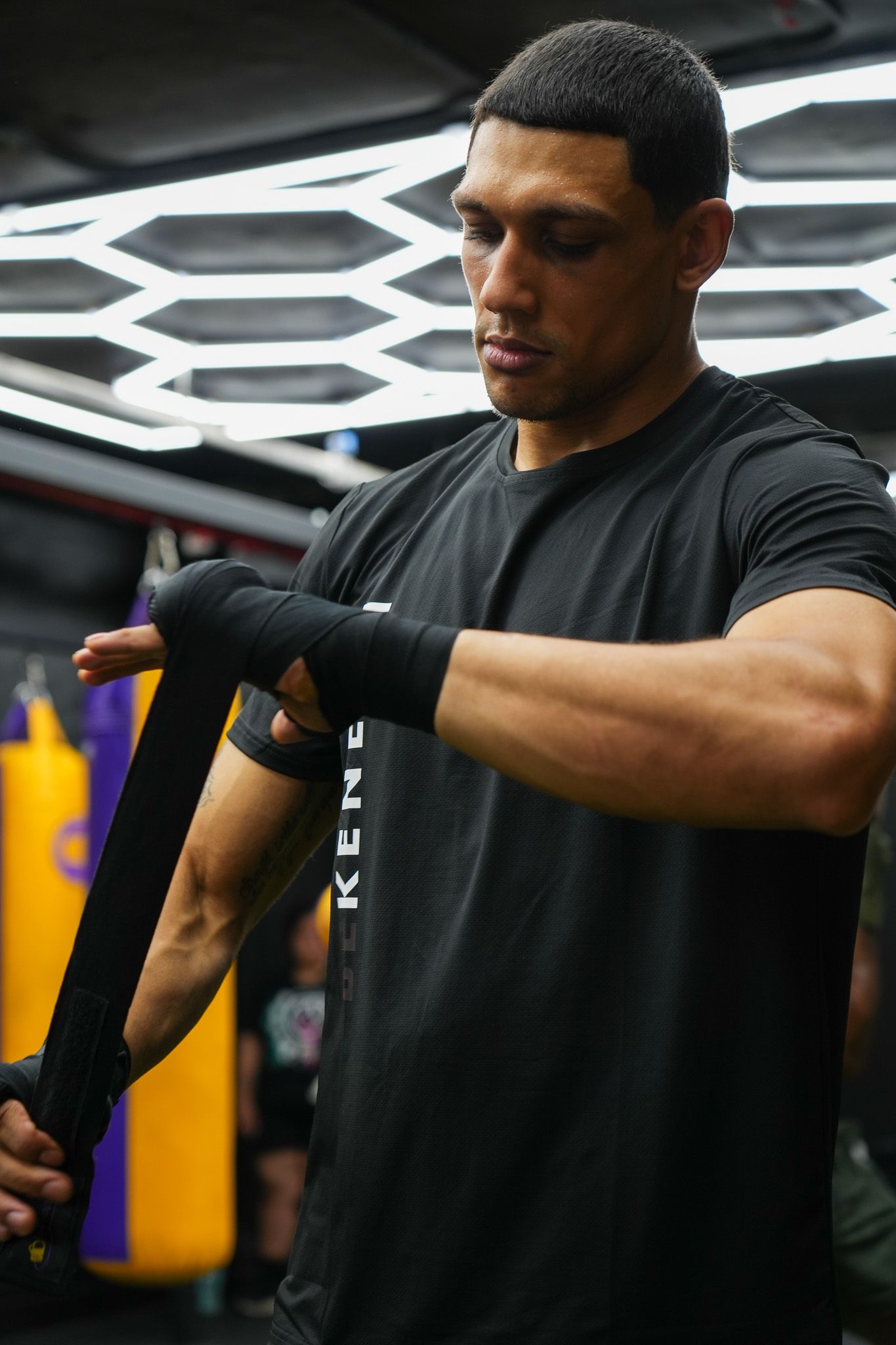 Athletic figure in black t-shirt practicing boxing combinations in a gym setting.