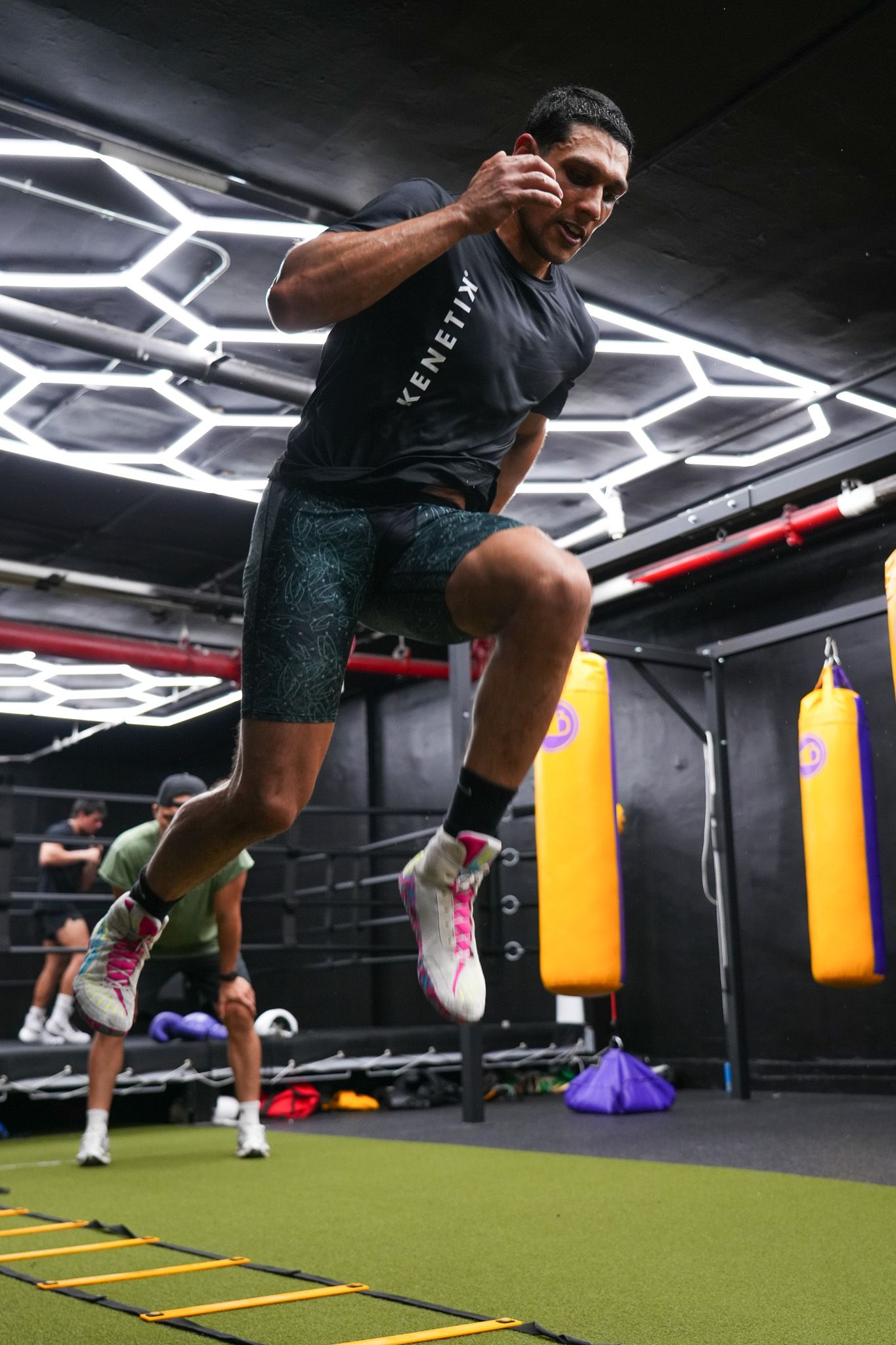 Athlete performing agility drills on ladder markers in modern fitness facility.