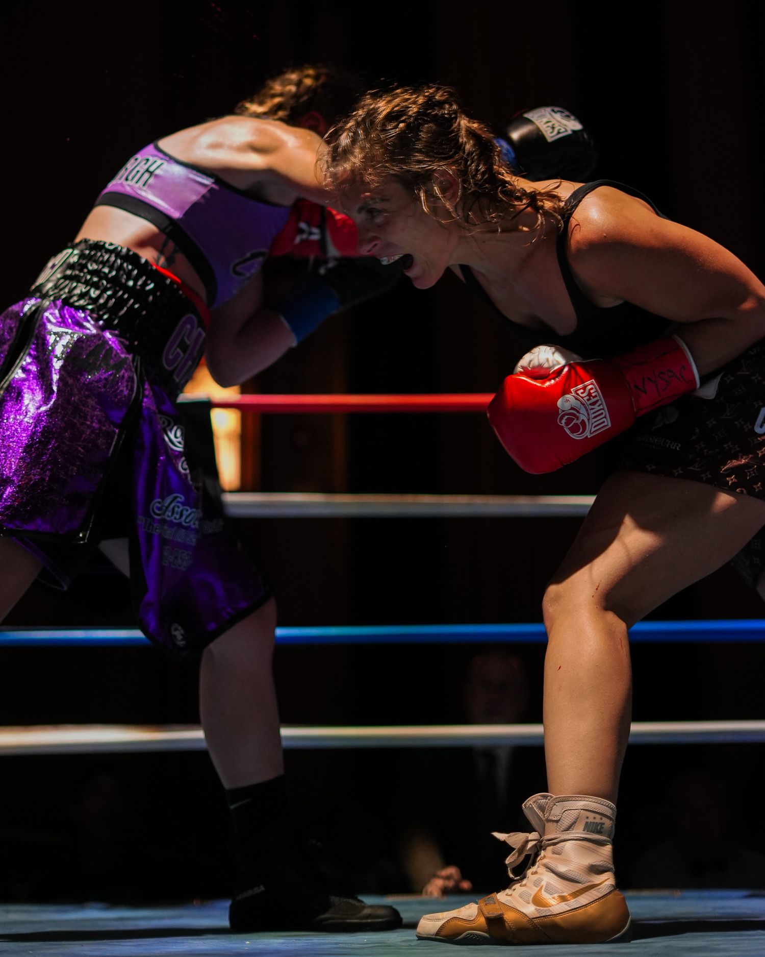 Two fighters engaged in an intense boxing match on a professional ring.
