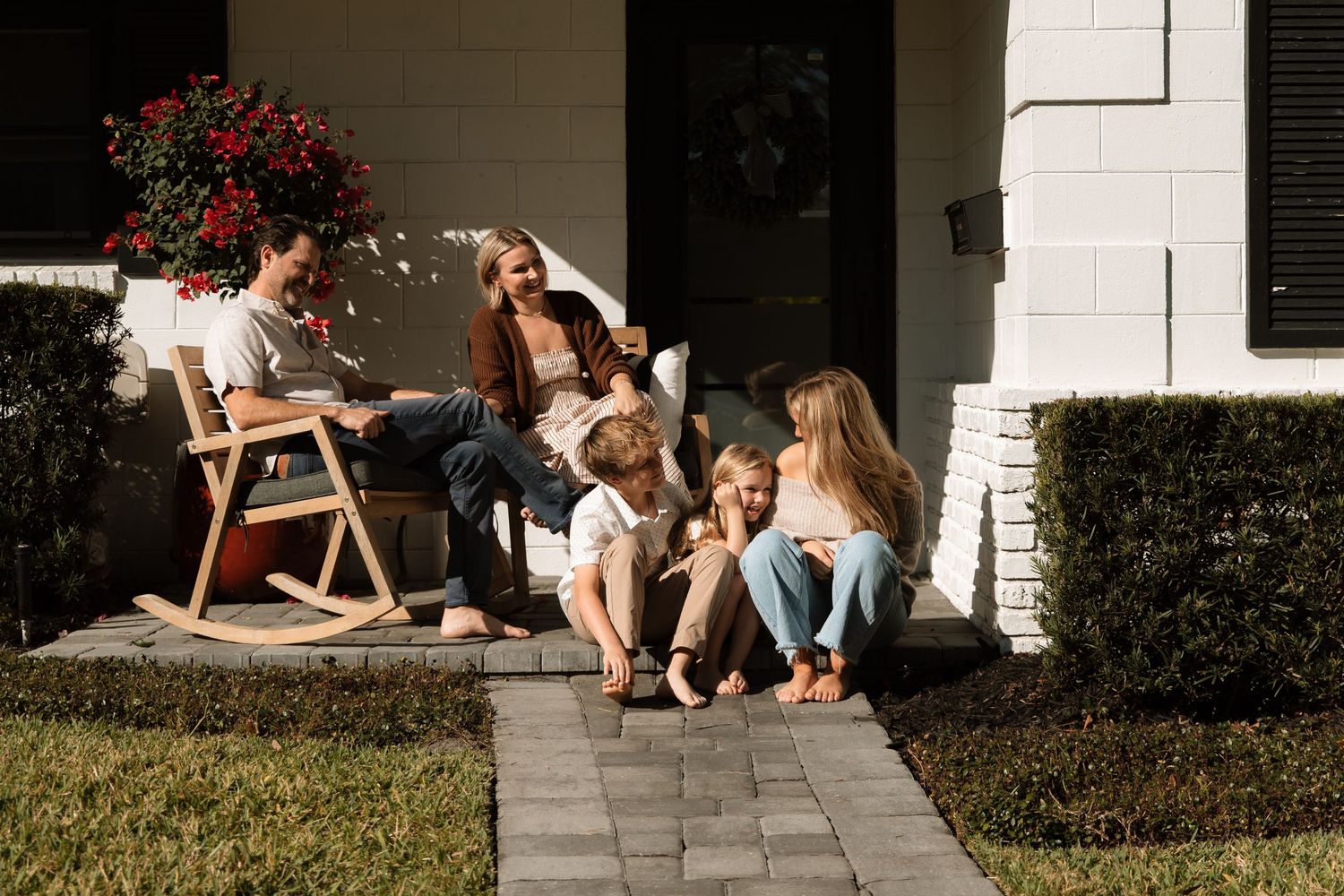 Happy family relaxes together on their front porch on a sunny day.