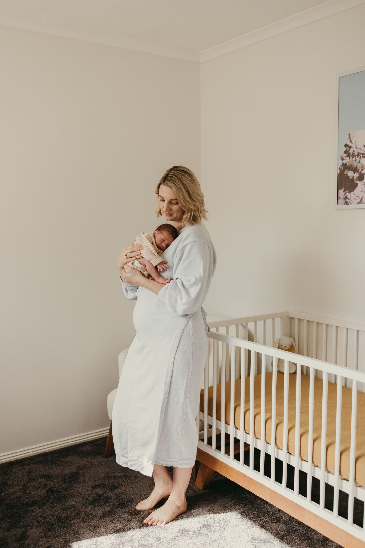 Tender moment in a minimalist nursery with white walls and wooden crib.