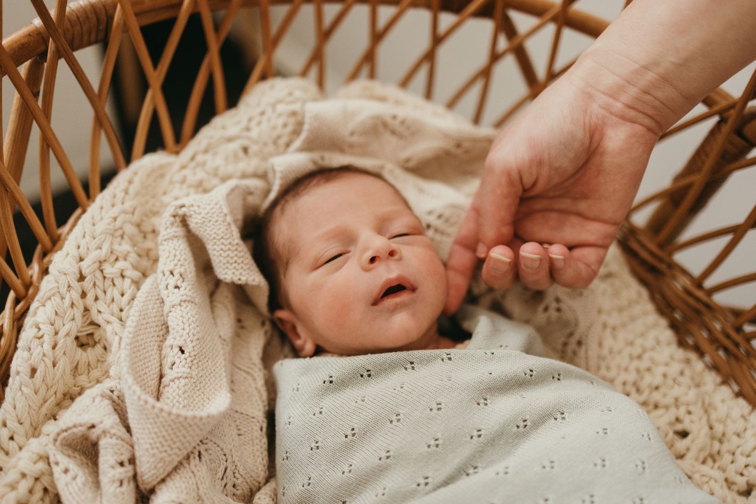A family portrait in a minimalist nursery with white walls and a wooden crib.
