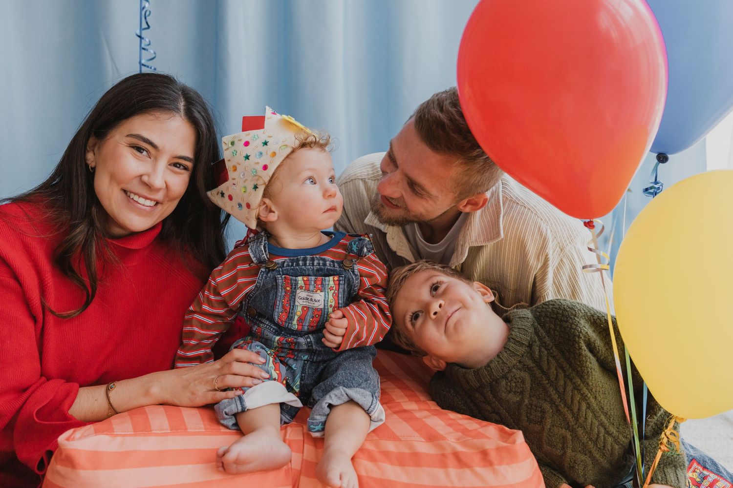 Geelong first birthday photography - family celebrating their baby's first birthday with colourful balloons and a party hat.