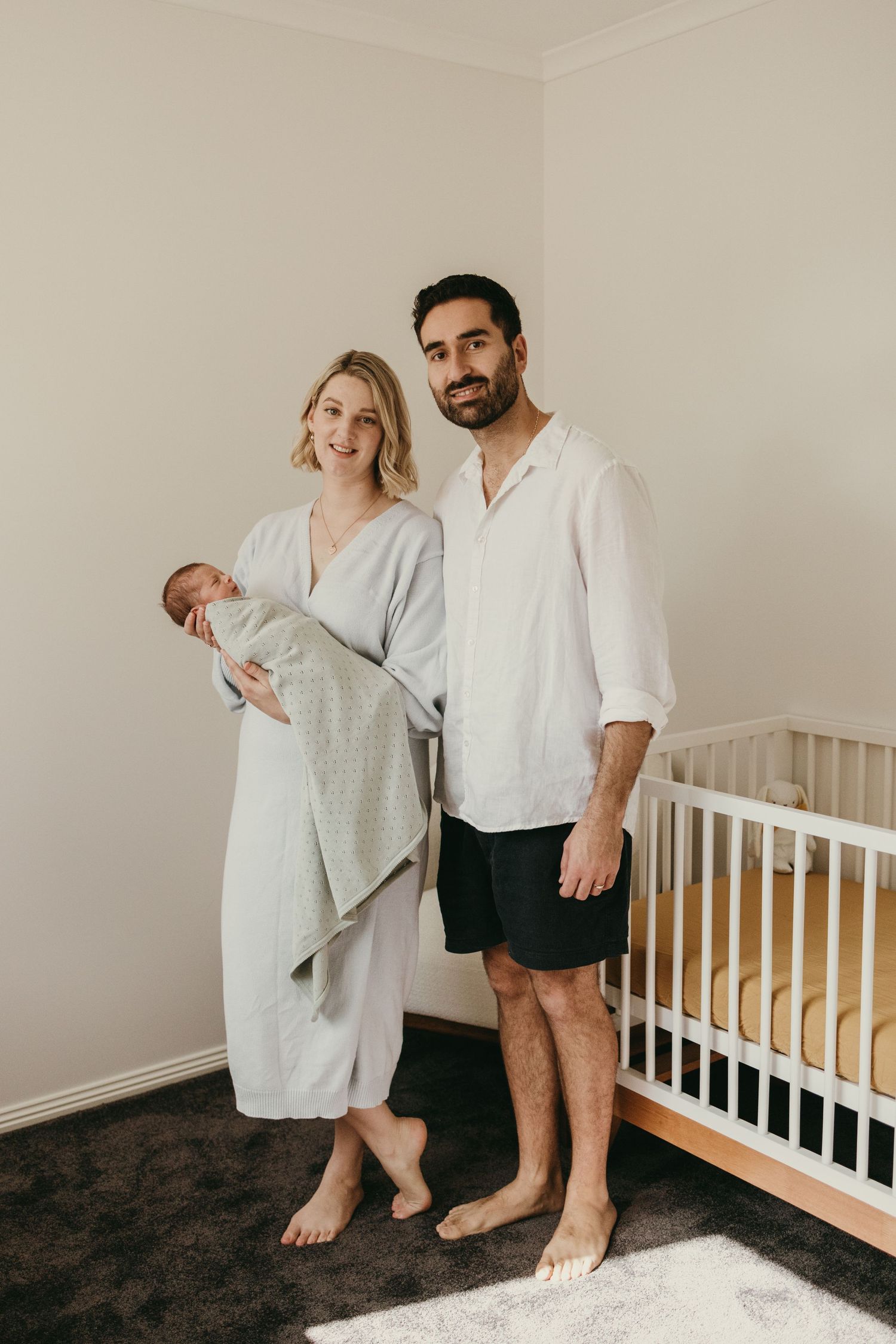 An intimate family moment showing parents gazing lovingly at their swaddled newborn.