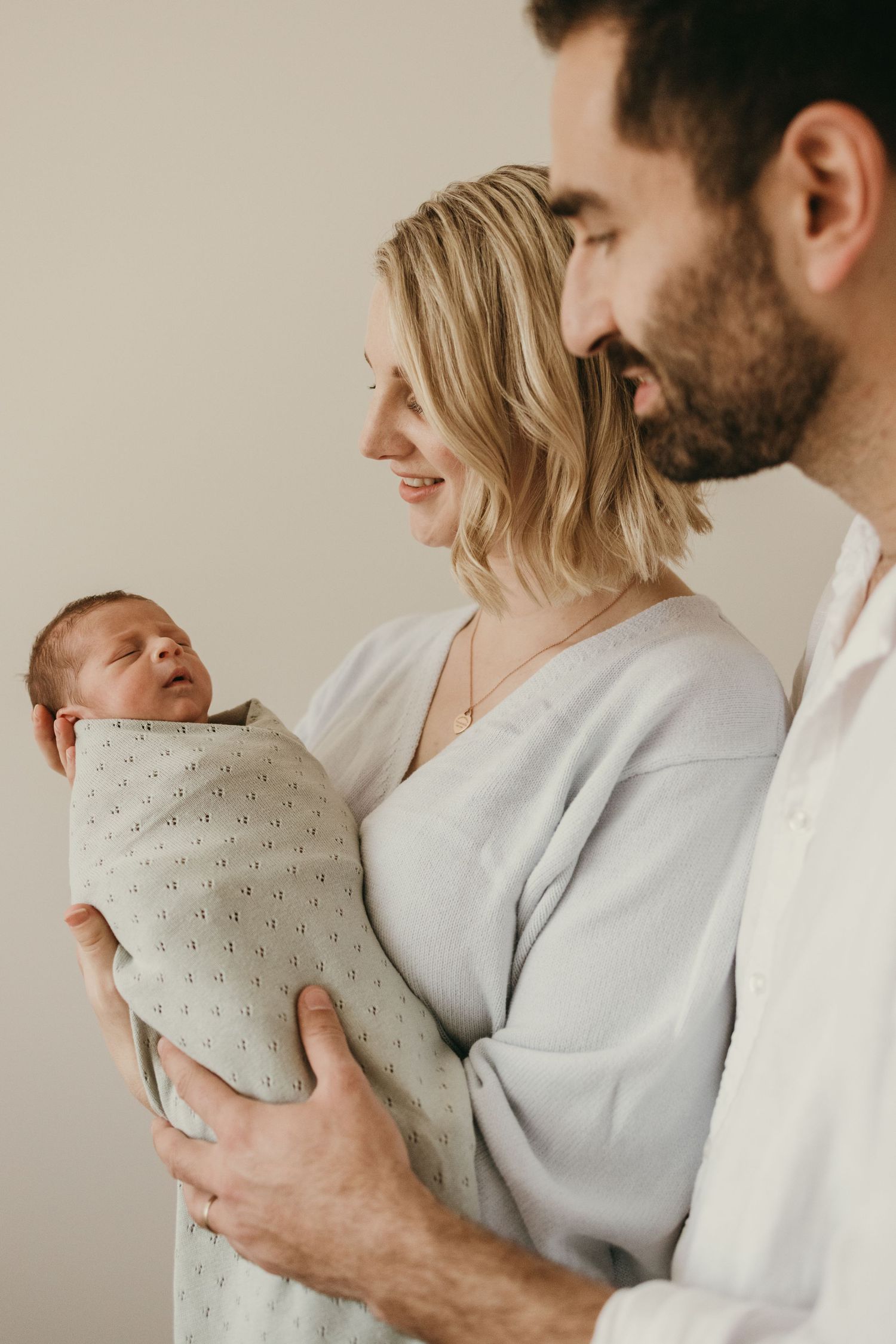 Parents sharing an intimate moment with their newborn in a minimalist nursery setting.