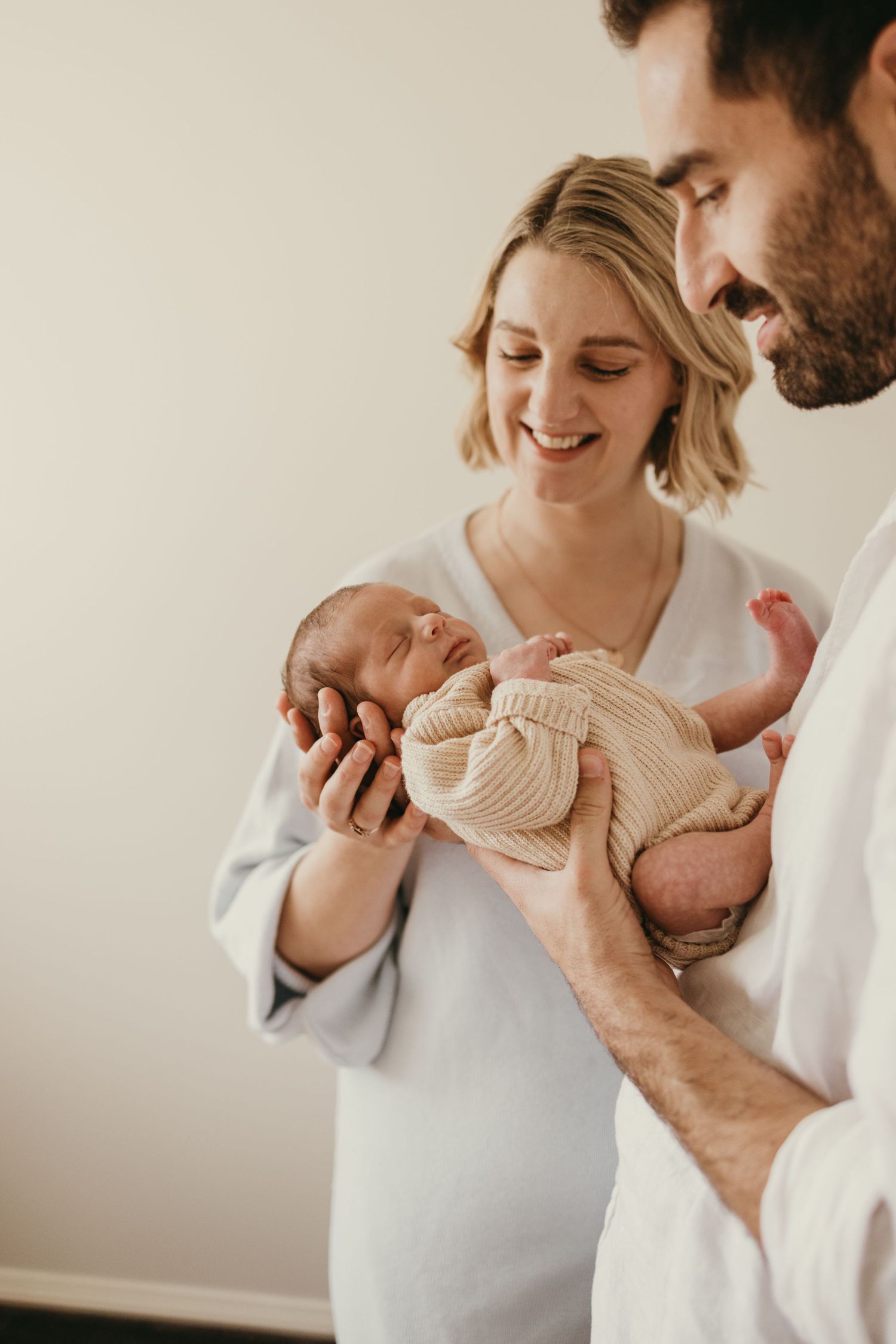 Intimate moment as parents look down at their swaddled newborn with joy and tenderness.