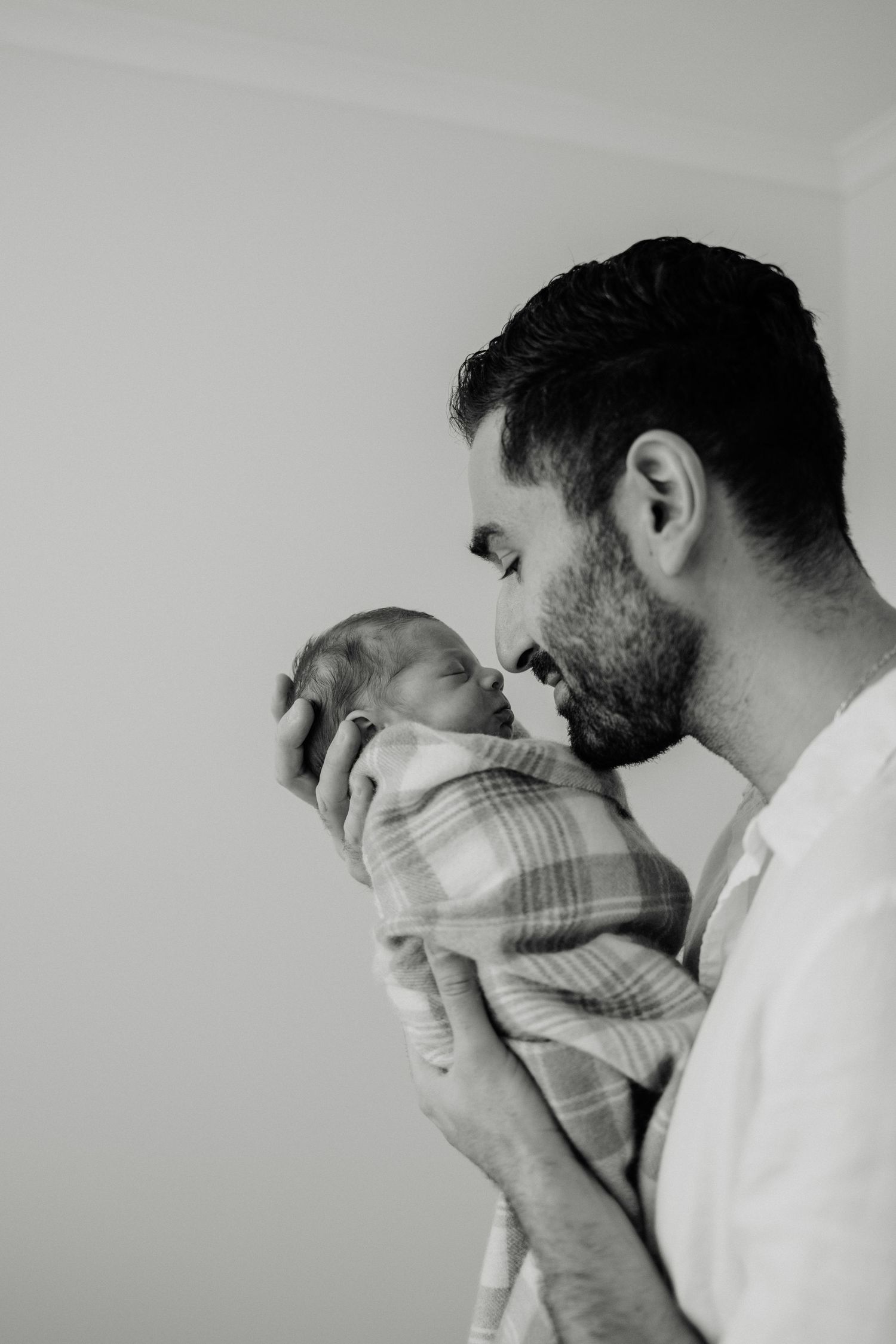 Black and white image of an intimate moment between parent and swaddled infant.