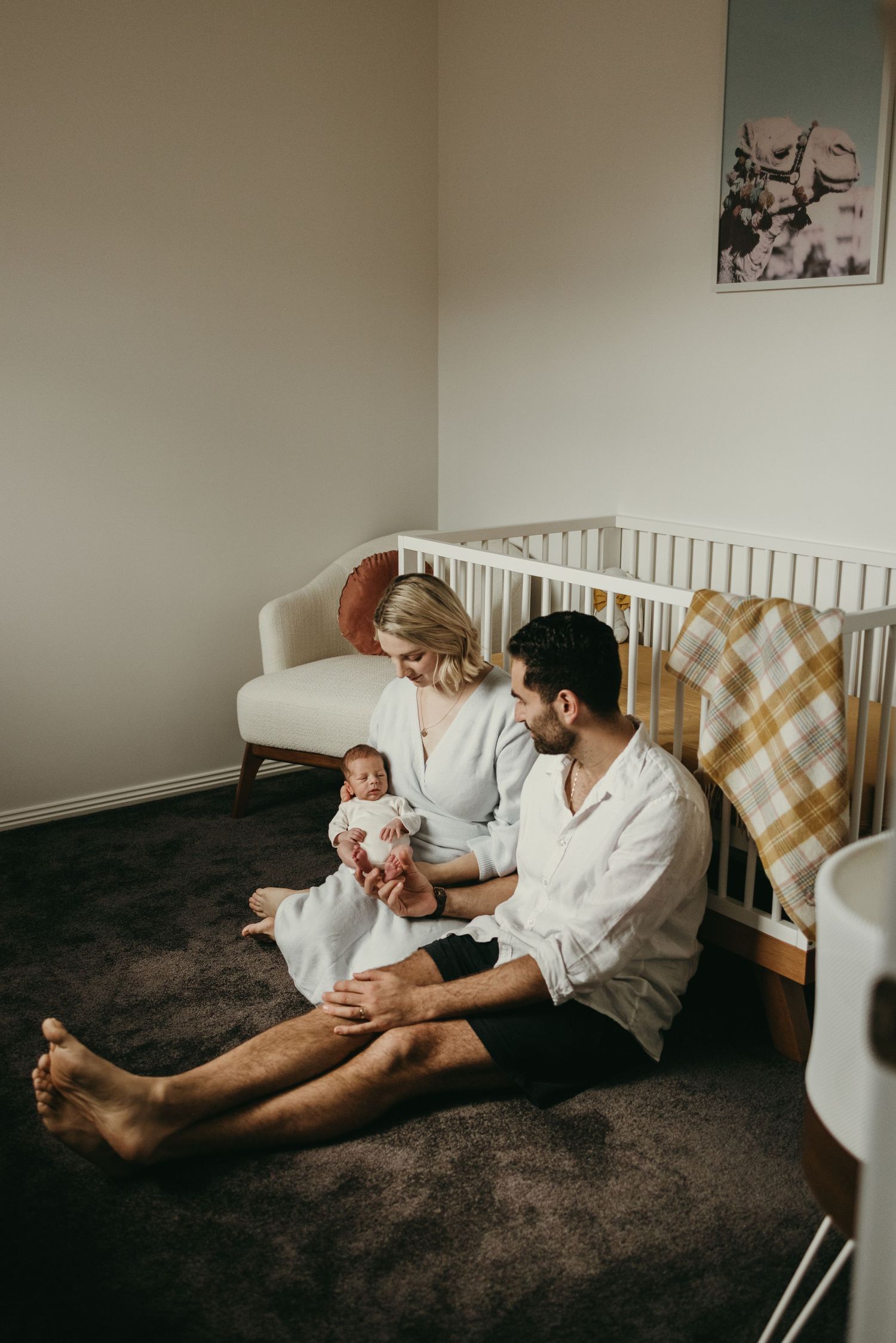 Family moment in nursery with white crib and dark carpet.