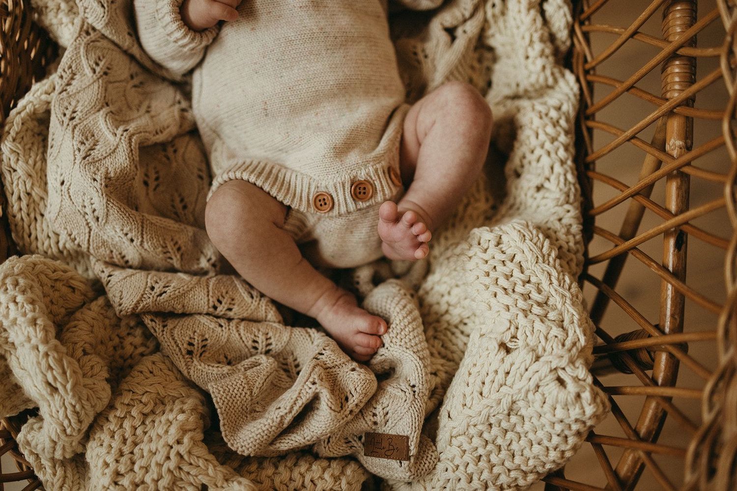 Geelong newborn photography - newborn baby in a cream knit romper on a chunky knit blanket in a wicker basket.