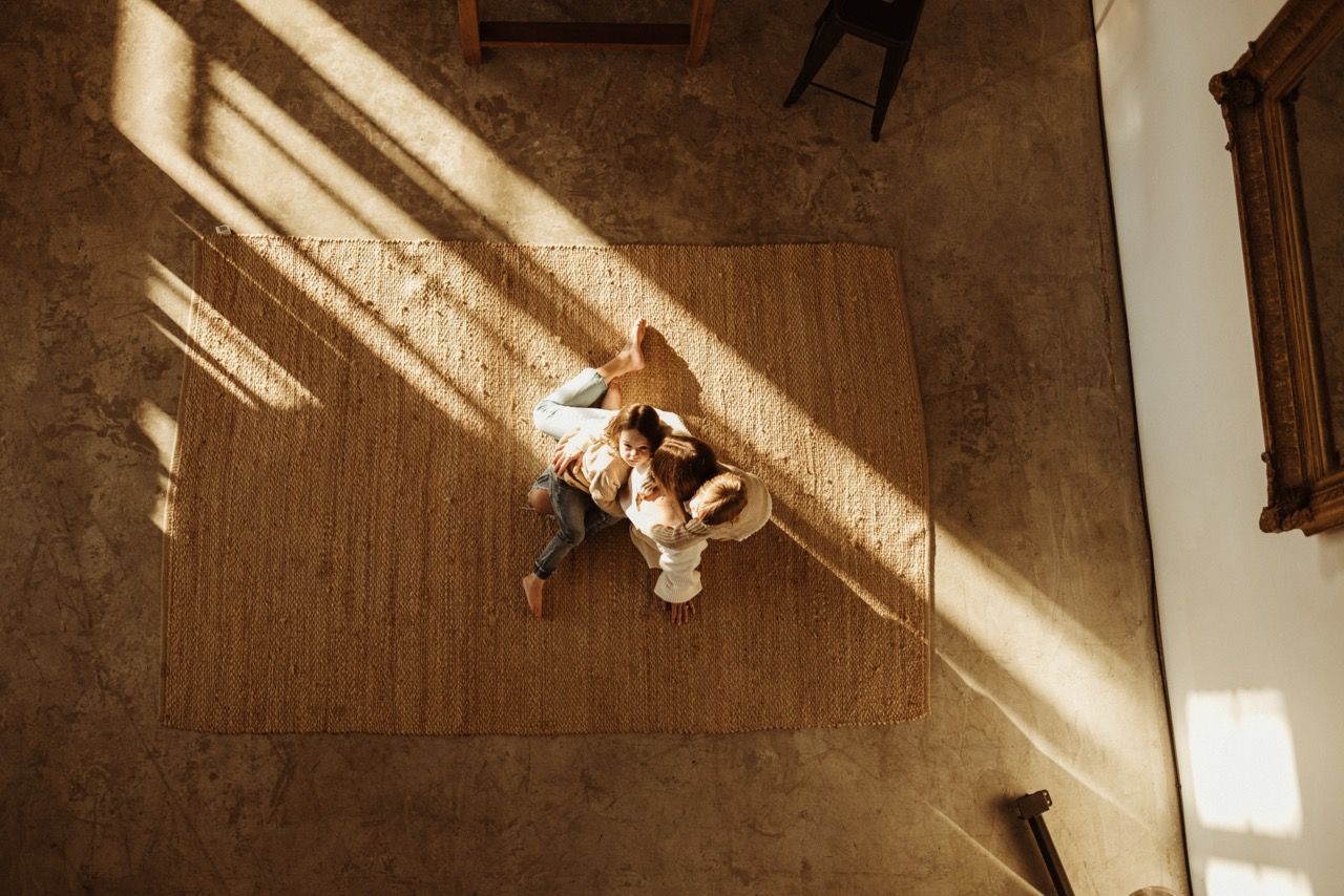Overhead view of family lounging together on wooden floor in sunlit room.