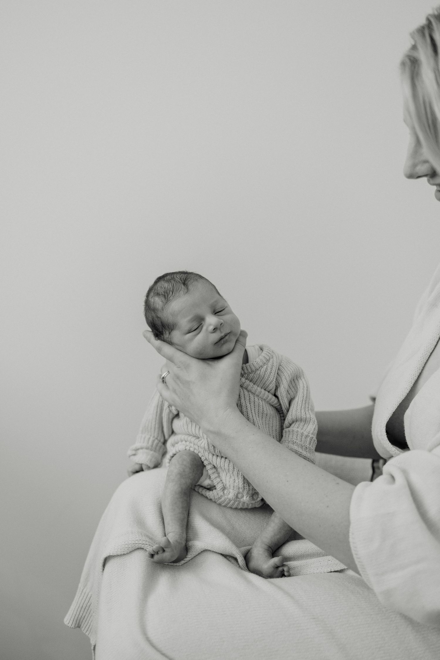 Black and white portrait of newborn baby being cradled gently.