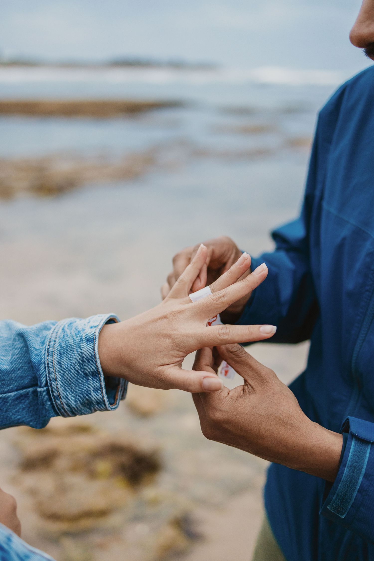 Couple exchanging rings on a beach, symbolizing a romantic proposal by the ocean shore.