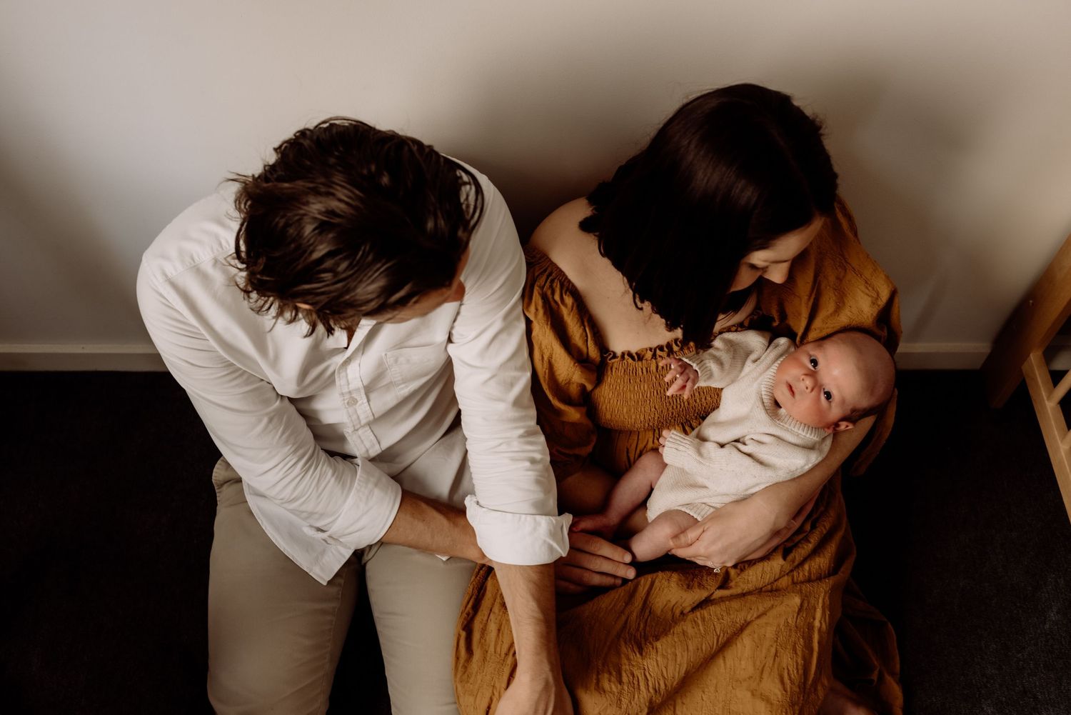 Two parents lovingly gazing at their newborn baby during a warm family lifestyle photography session.