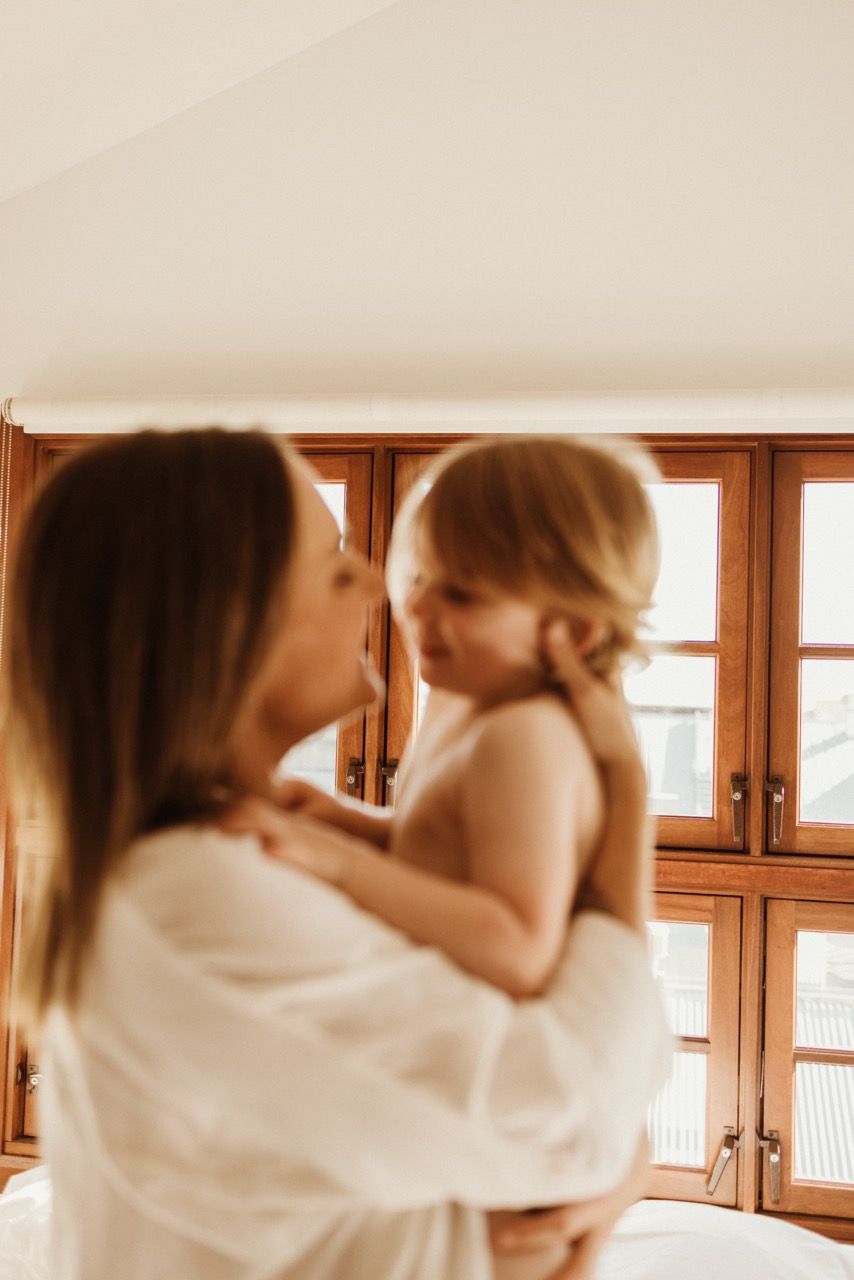 Warm sunlit moment captured against wooden window backdrop in bedroom setting.