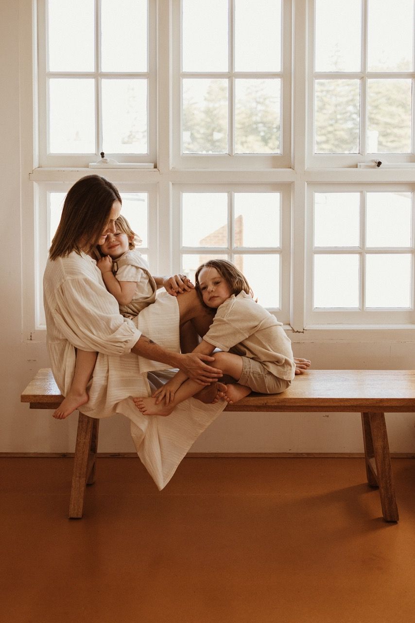 Family sharing tender moments together on wooden bench by bright windows.