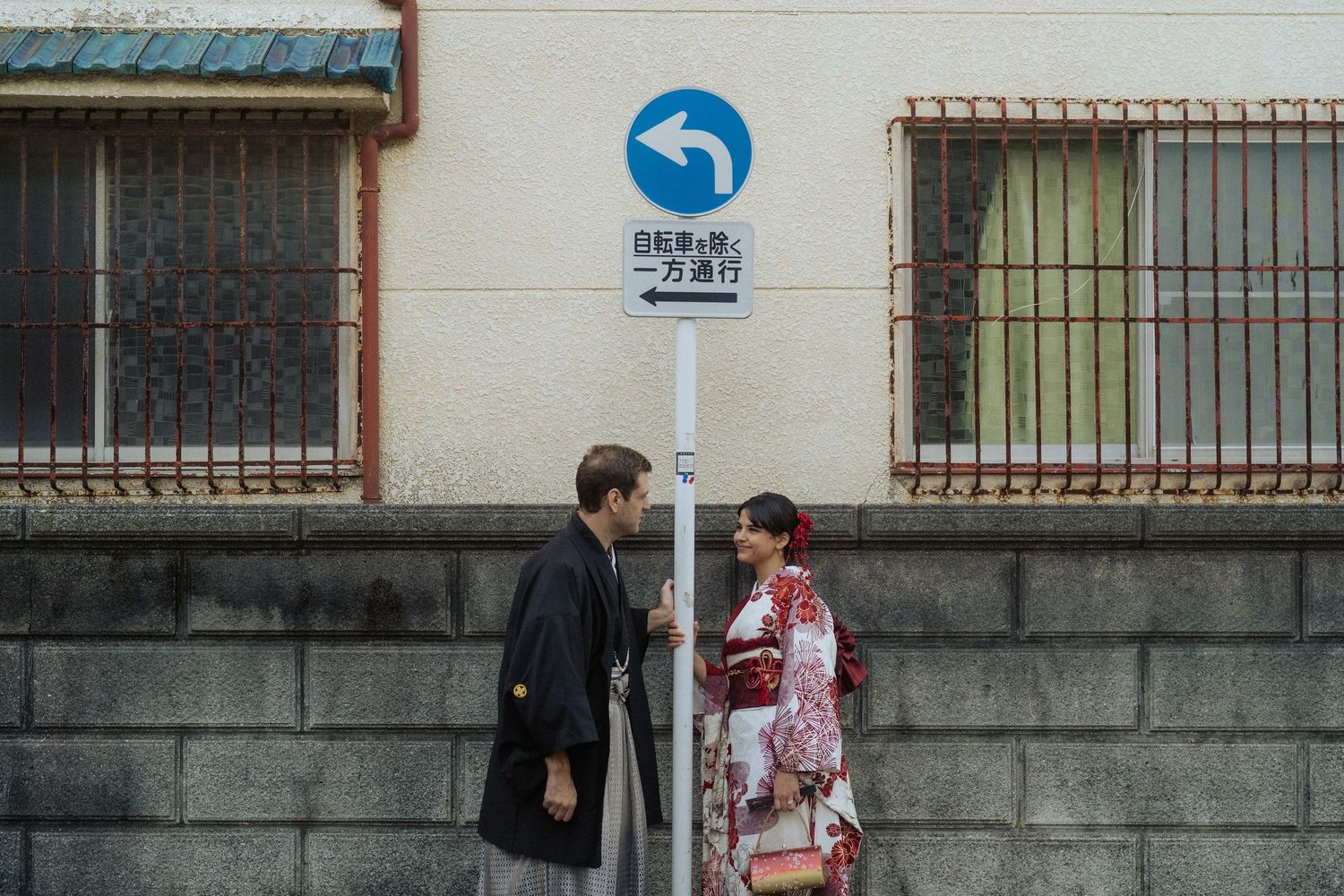Couple in traditional Japanese kimono standing by a one-way street sign in Japan.