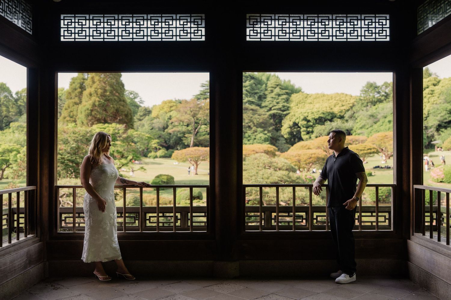 Couple standing in a traditional Chinese pavilion with lush garden views, captured during a maternity photo session.
