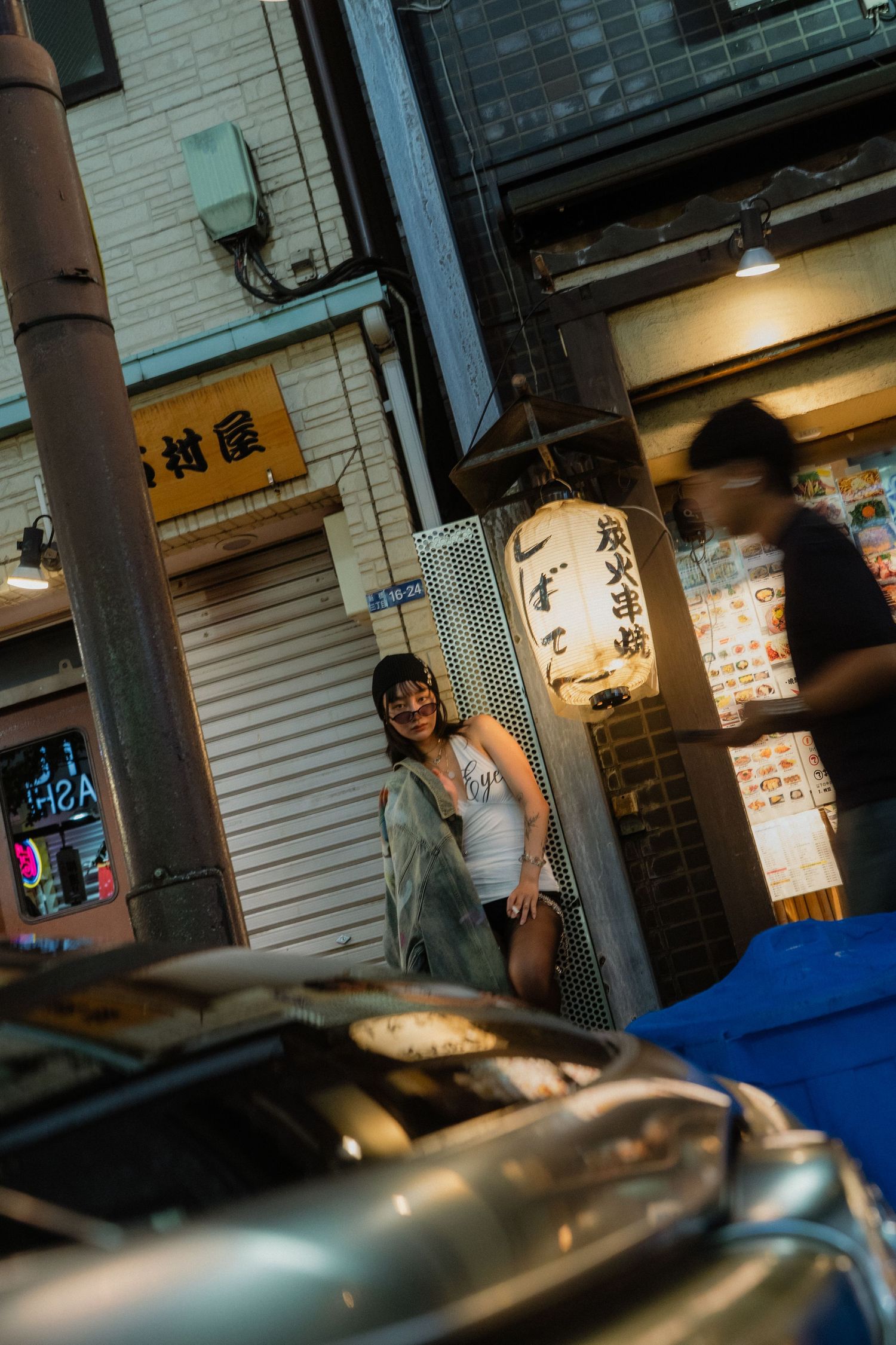 Woman smiling near a Japanese lantern sign outside a Tokyo restaurant at night.