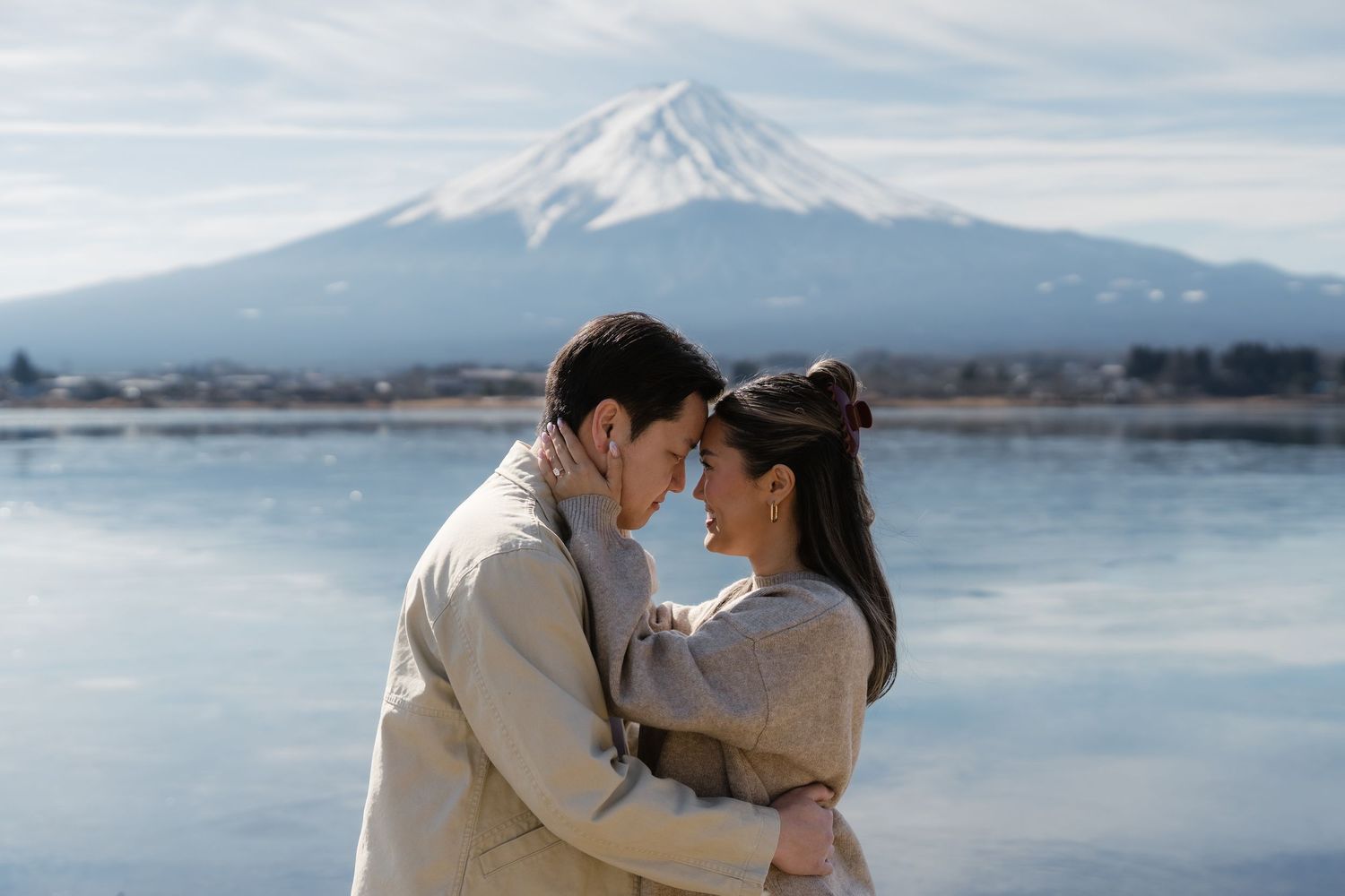 Couple sharing a romantic moment with snow-capped Mount Fuji and serene lake in the background.