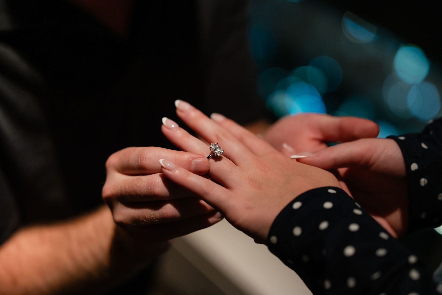 Close-up of a marriage proposal with a diamond engagement ring being placed on a woman's finger.
