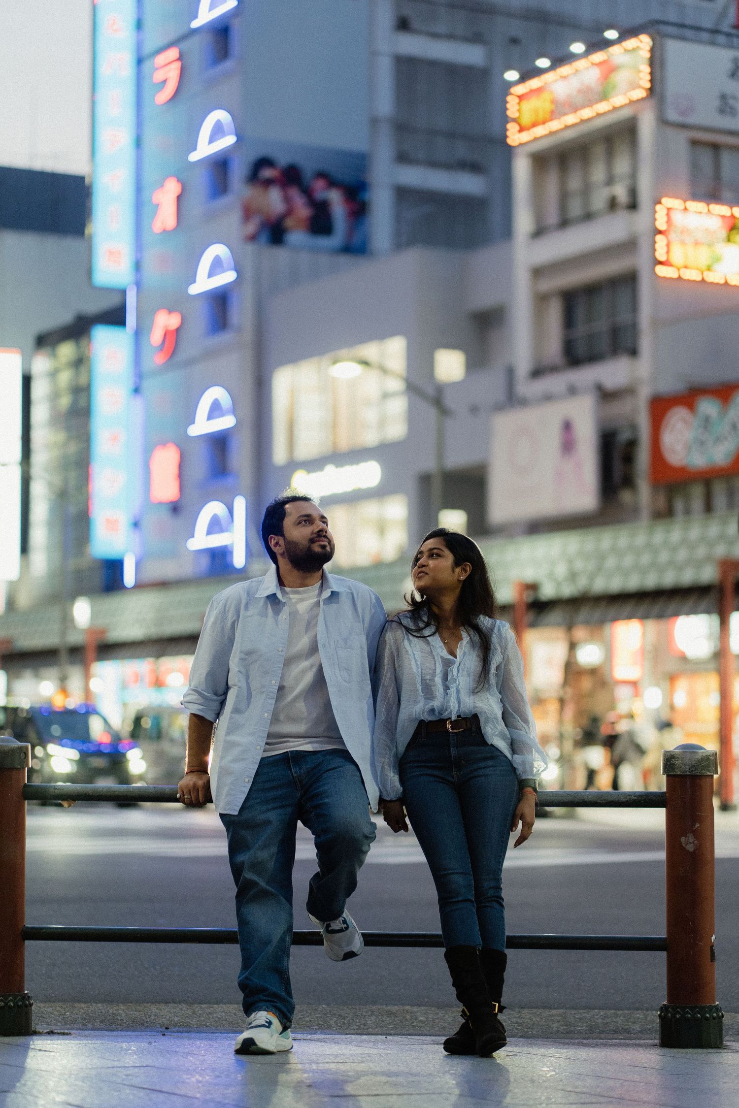 Couple walking together at night in a vibrant city street with neon signs and illuminated buildings.