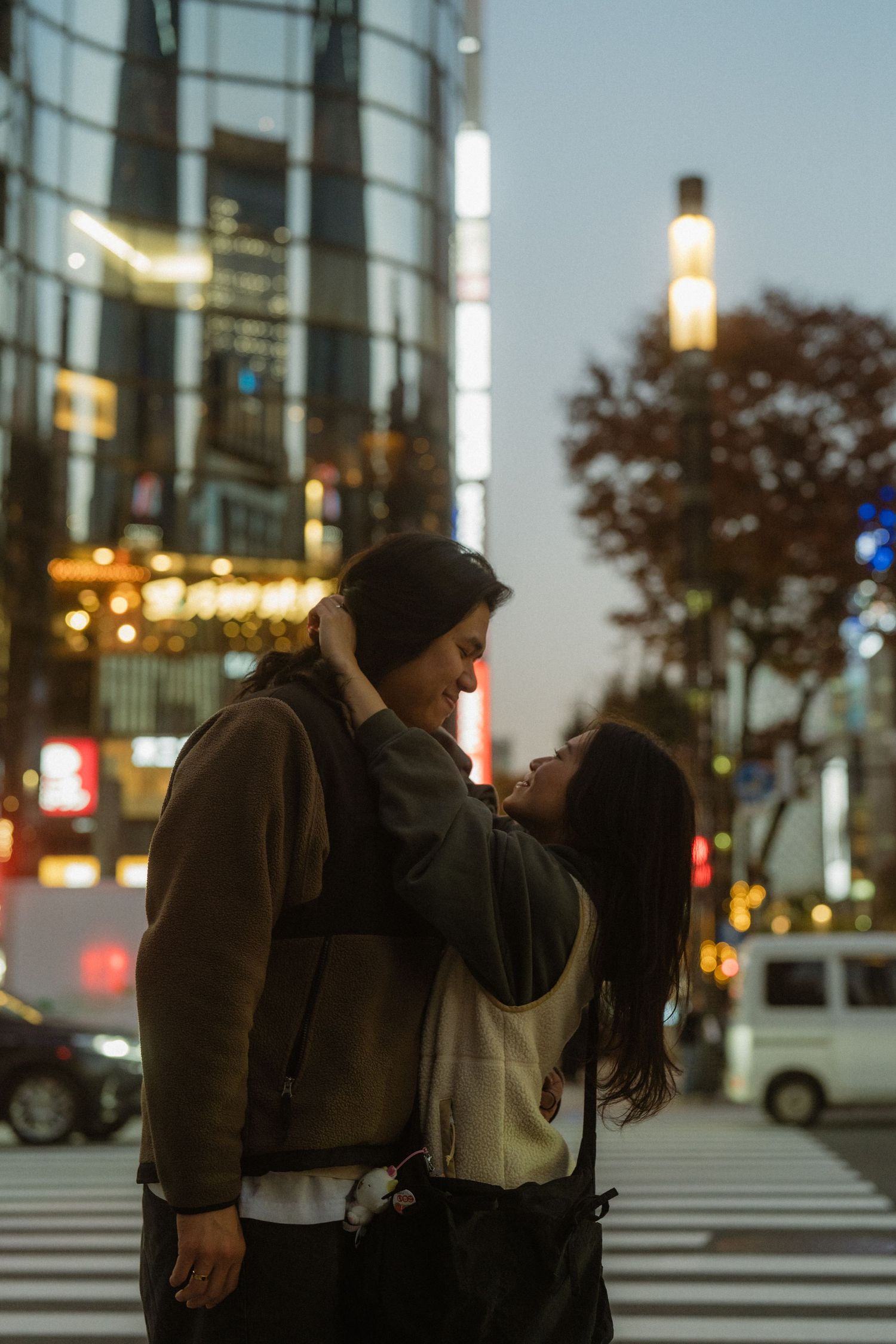 Couple sharing a romantic moment on a city street at night with glowing urban lights in the background.