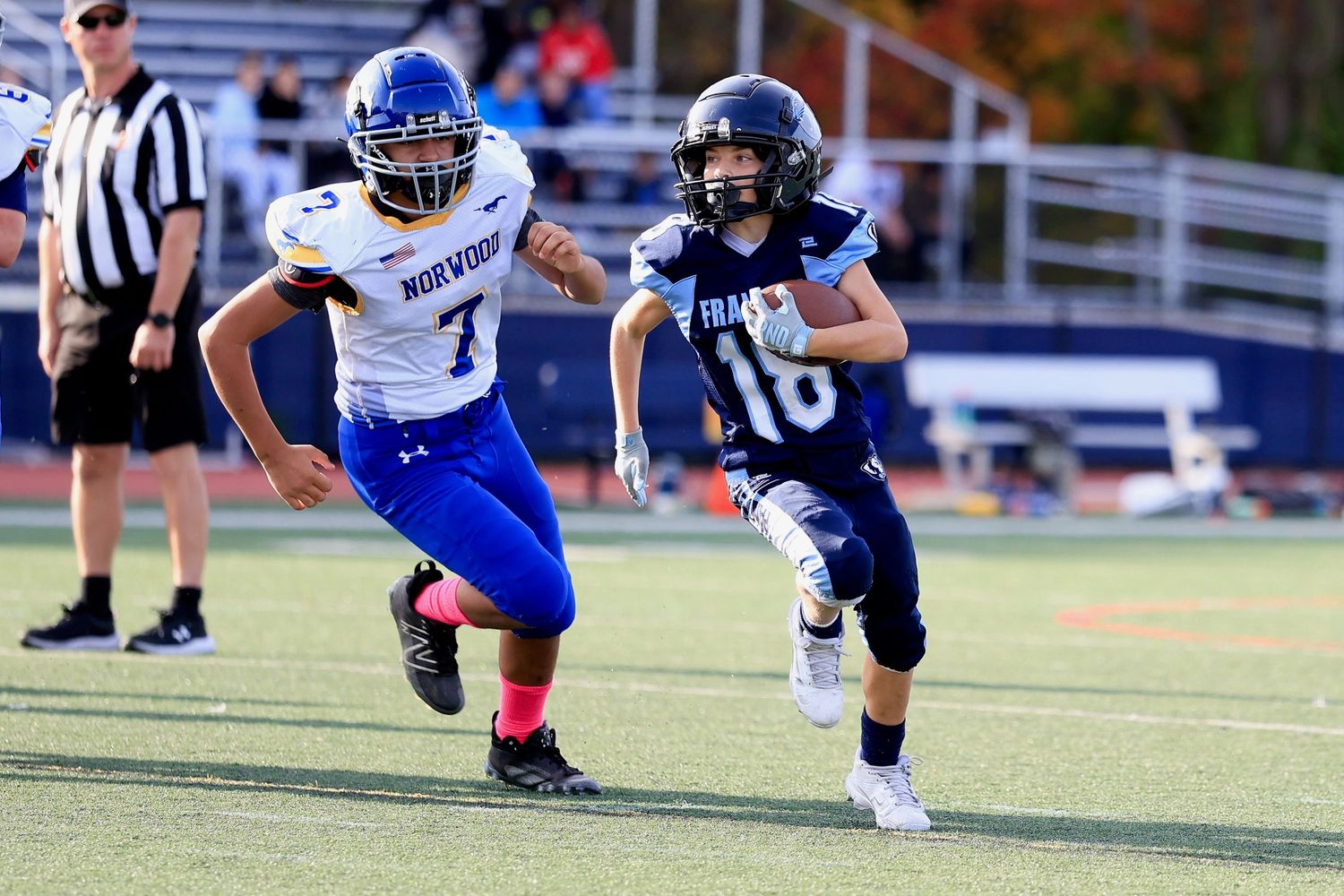 Youth football player in Franklin jersey running with the ball during a game.
