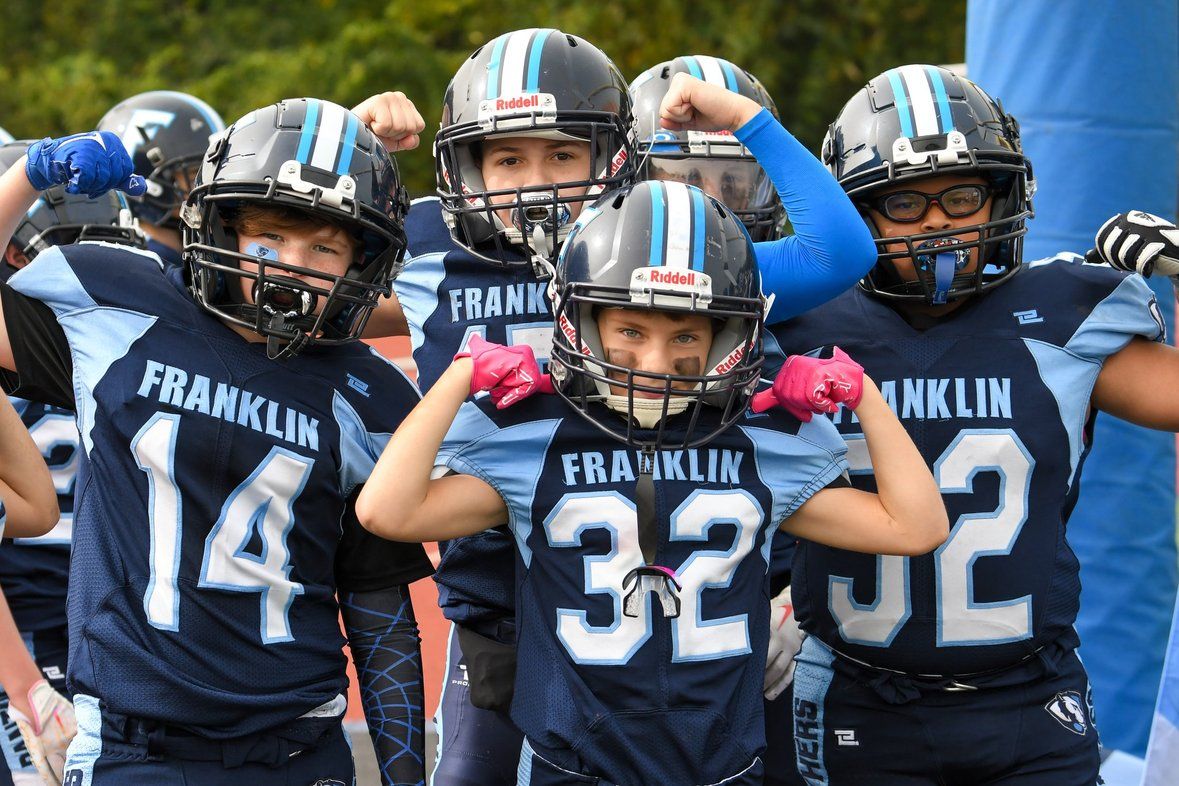 Youth football players in Franklin uniforms flexing and celebrating on the field.