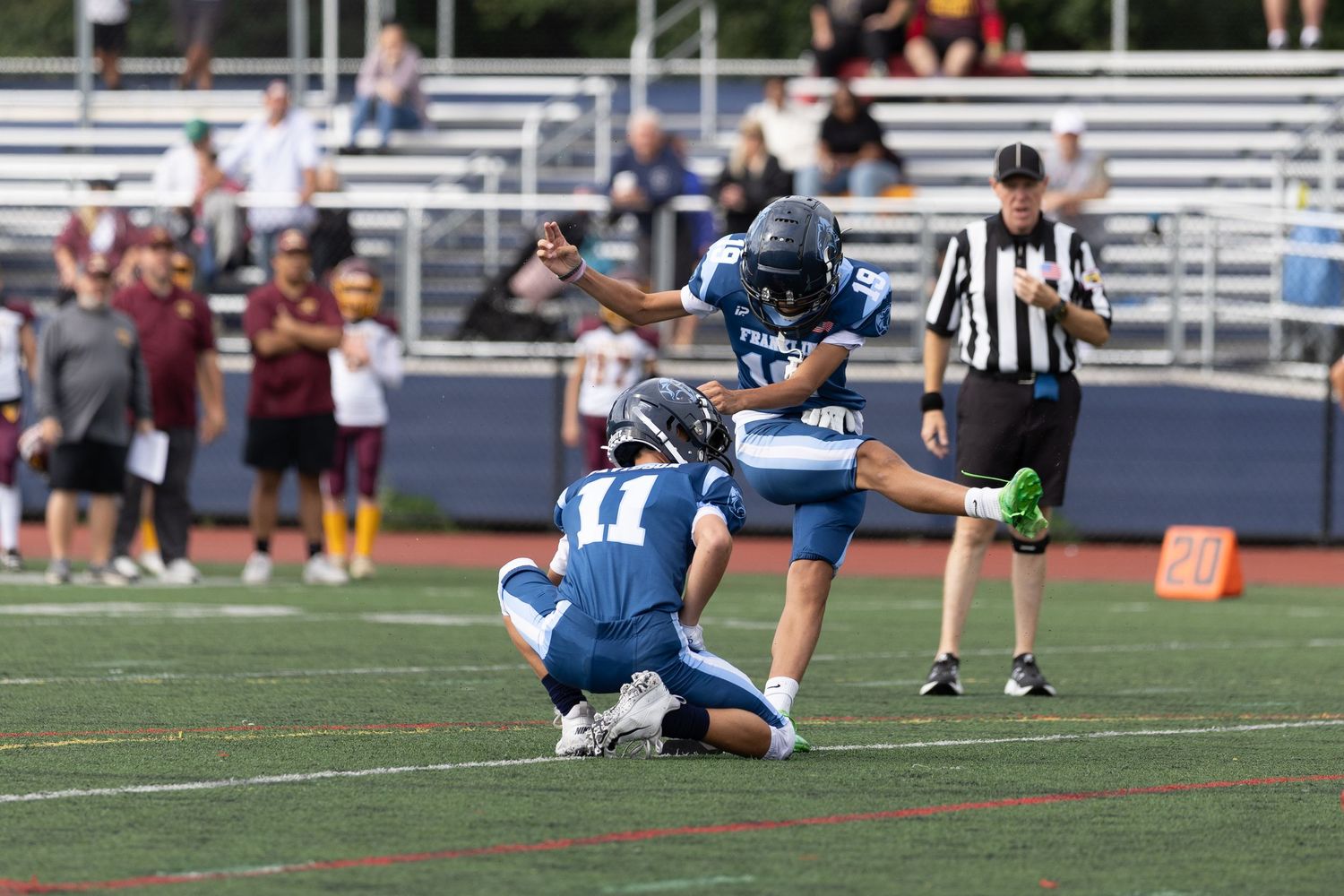 Football player attempting a field goal kick during a sunny outdoor game.