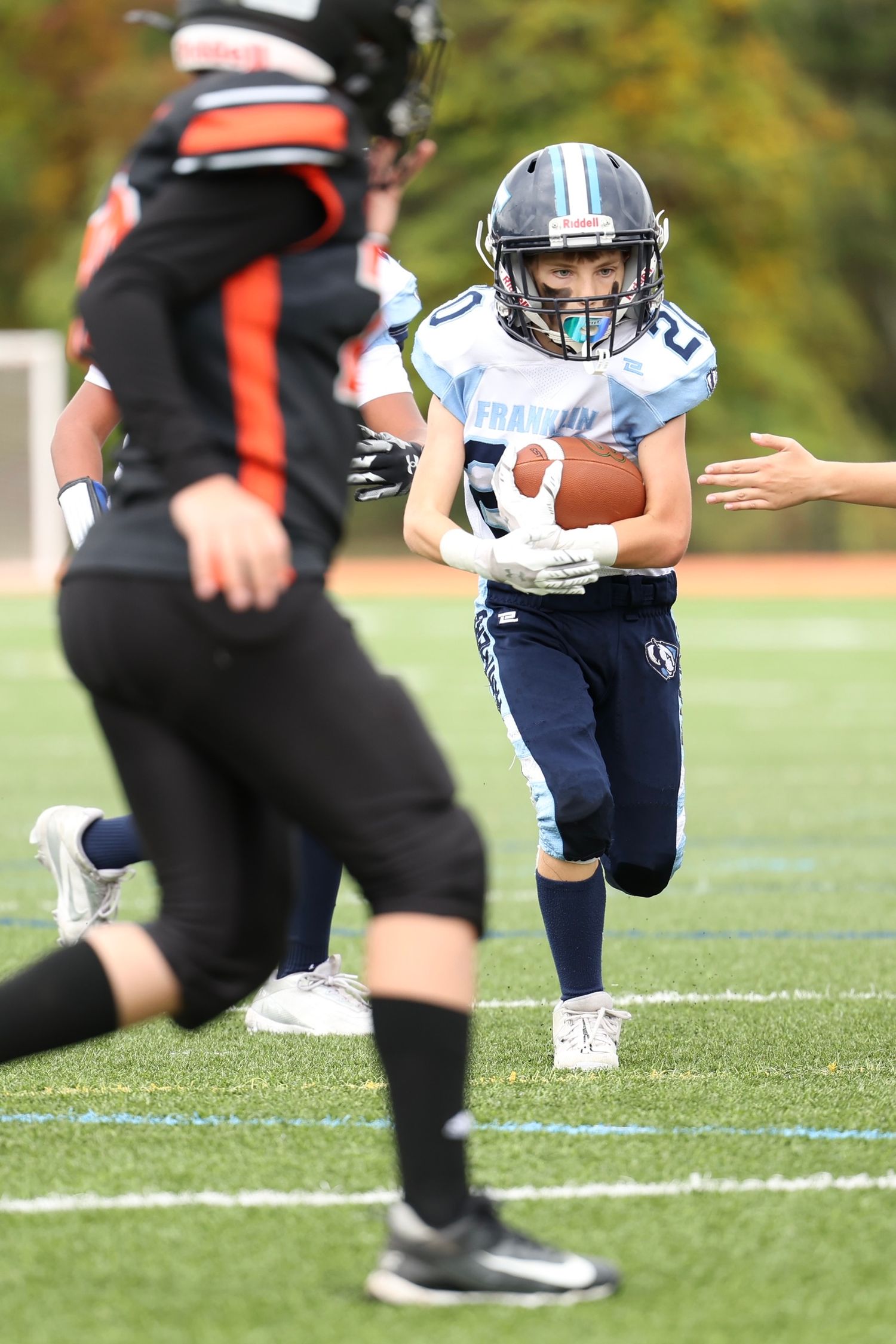 Youth football player in blue Franklin Panthers jersey running with ball.