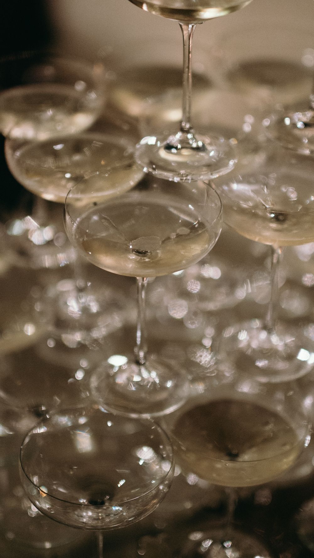Elegant champagne tower with crystal coupe glasses stacked in pyramid formation at a celebration.