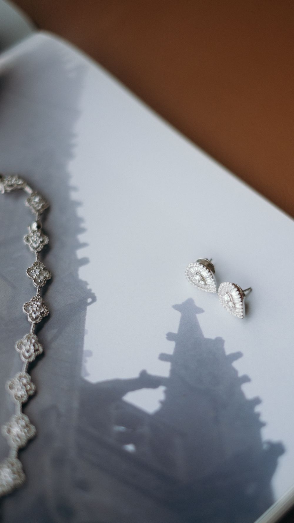 Silver filigree bracelet and teardrop crystal stud earrings displayed on white ceramic tray.