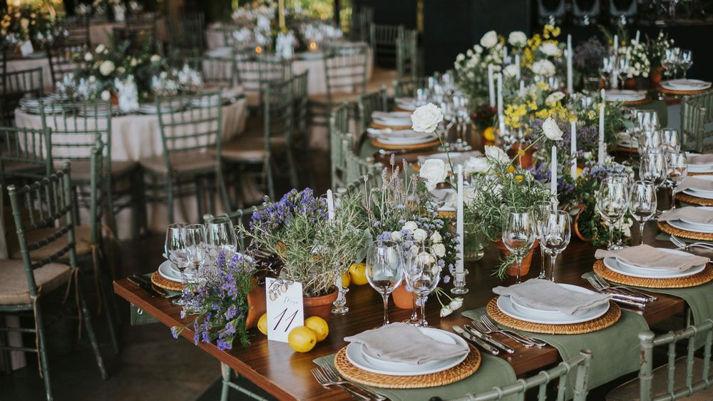Rustic wedding reception tables with sage green runners, lavender centerpieces, lemons, and chiavari chairs.