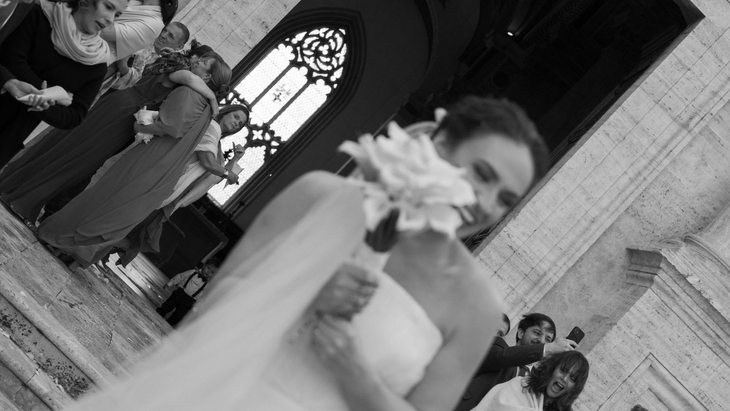 A black and white photo of a couple kissing at the altar during a church wedding ceremony.