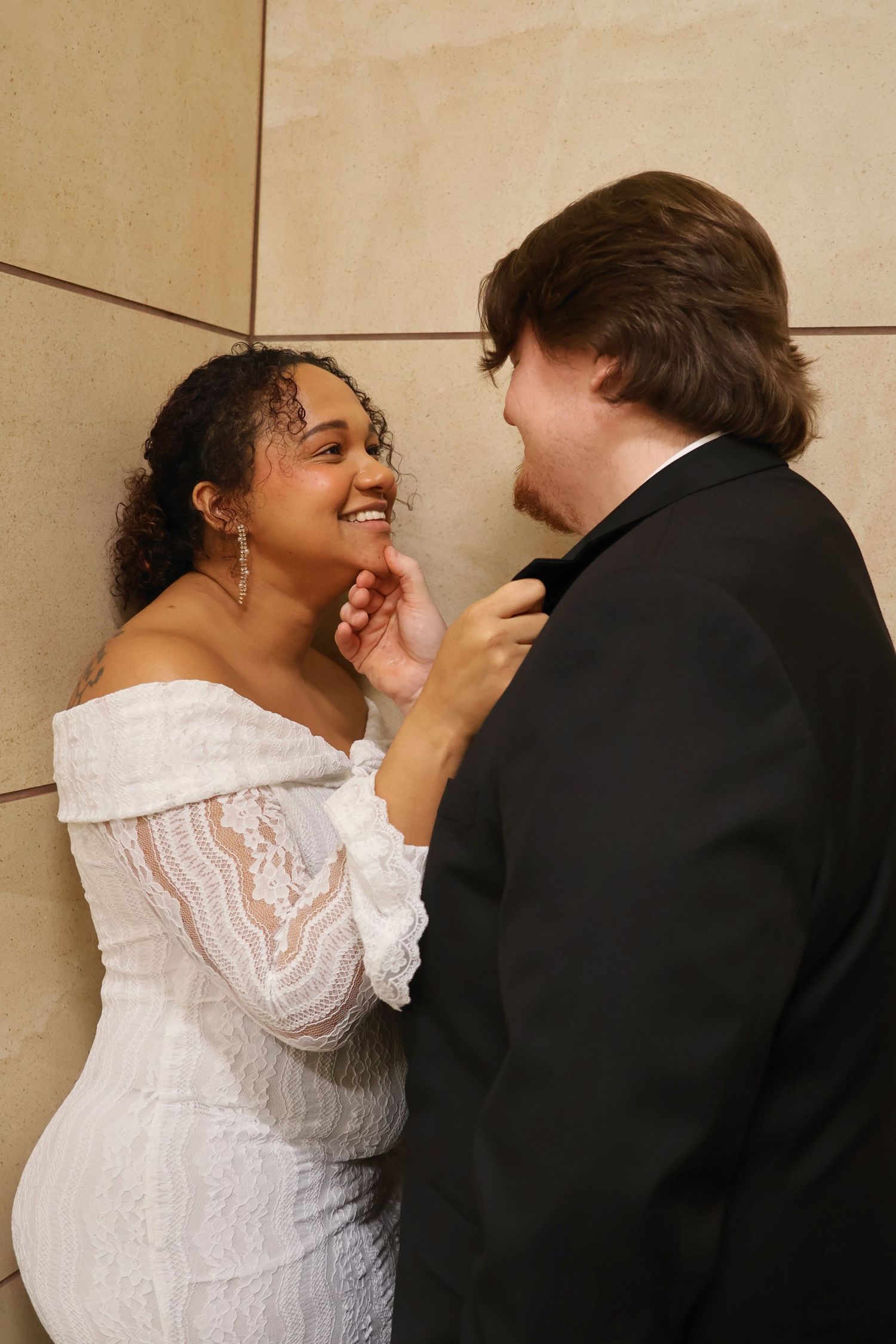 A newlywed couple sharing an affectionate moment as the bride gently touches the groom's chin.