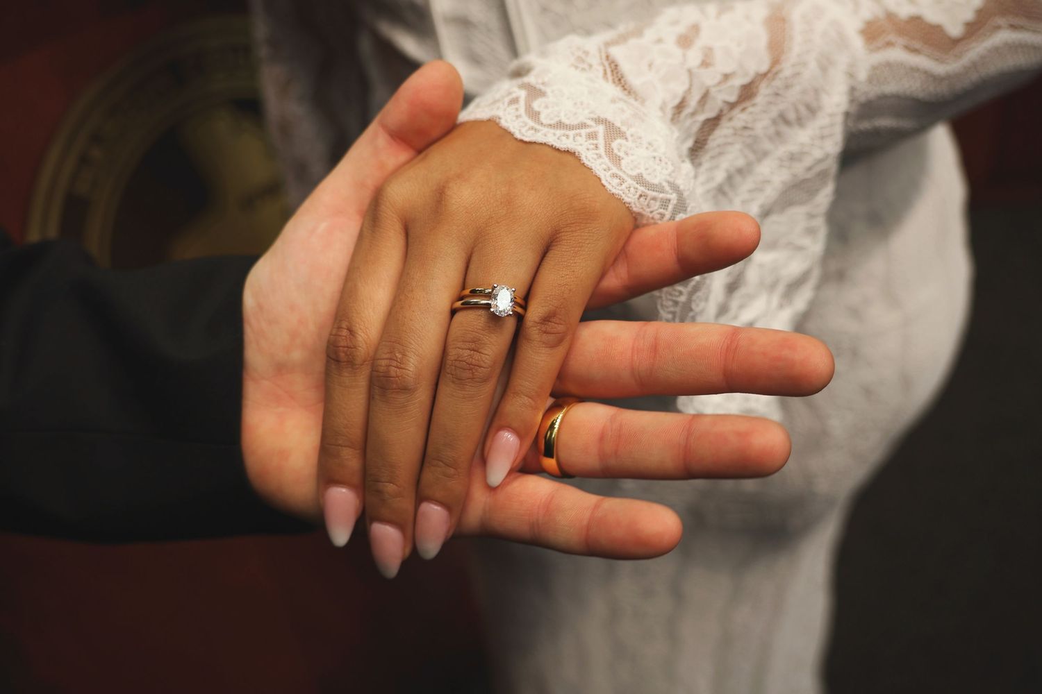 A close-up shot of the bride's hand resting over the groom's hand, displaying their wedding rings.