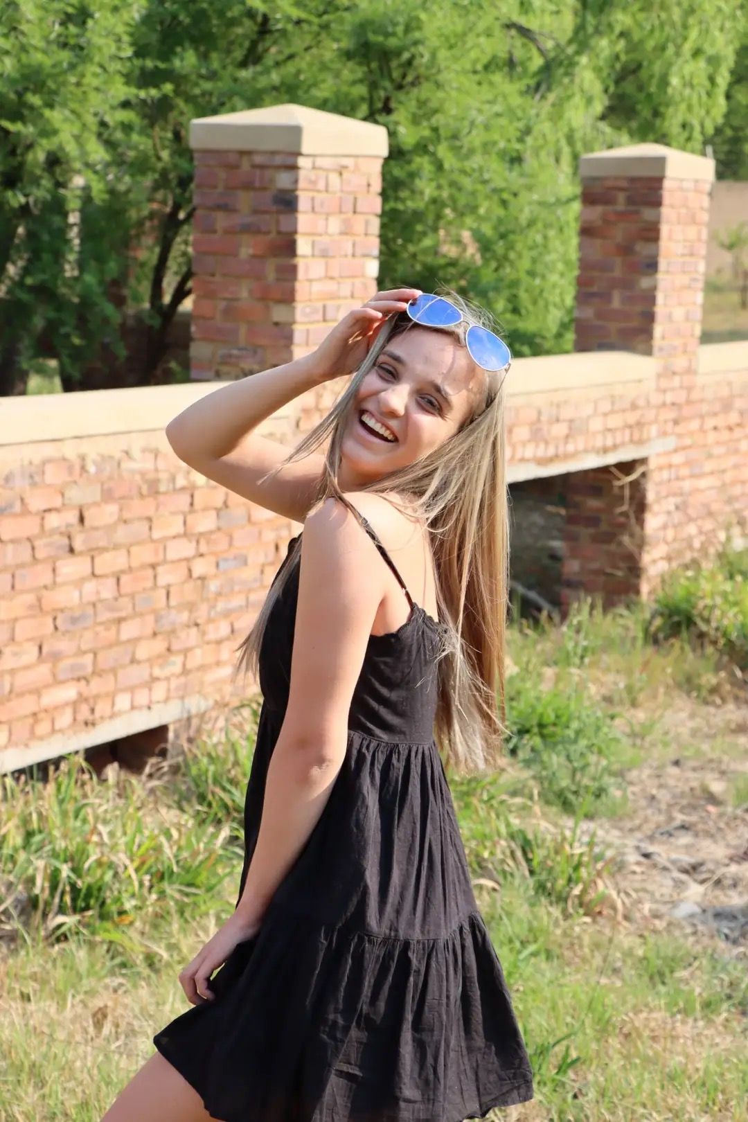 Girl Smiling holding her sunglasses