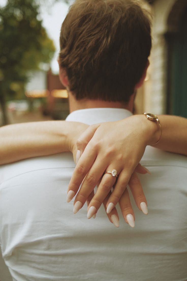 Engagement Ring on hand with woman holding her partners neck