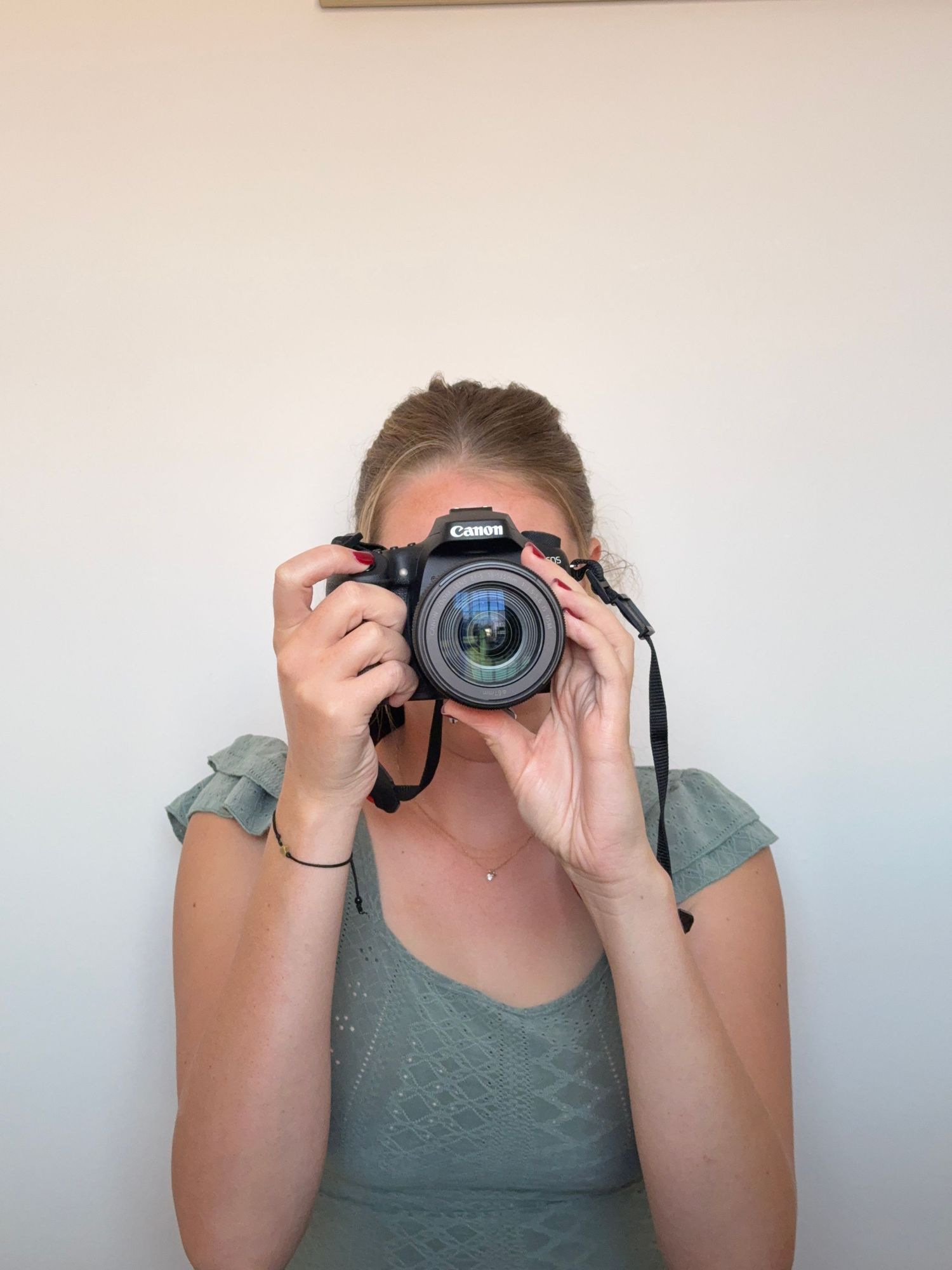 Blonde girl holding a cannon camera to her face, taking beautiful photoshoots in pretoria and business videography for marketing